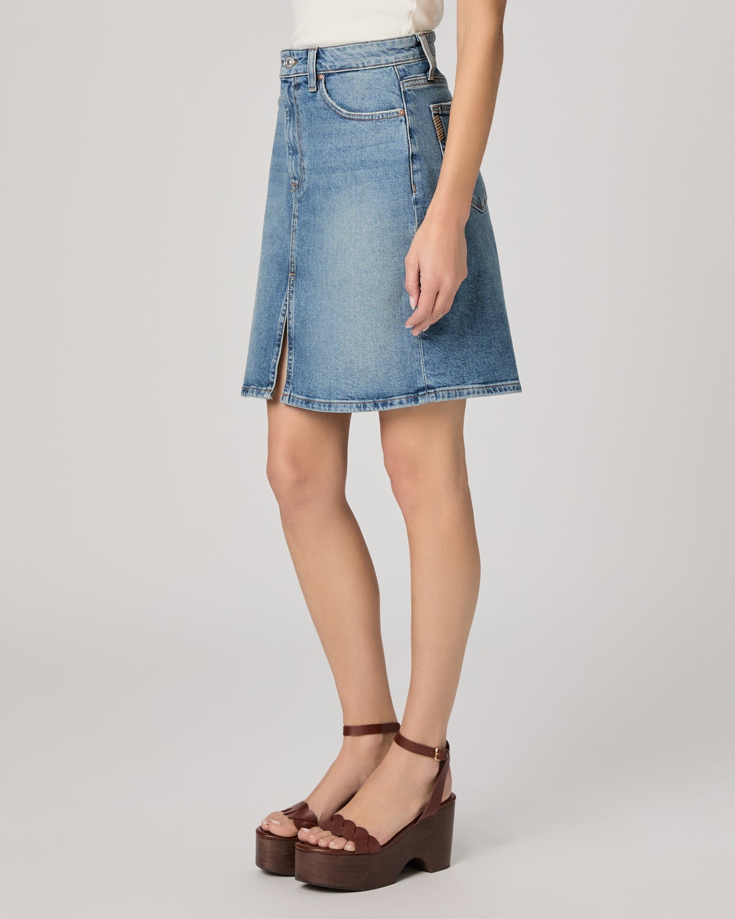 Denim skirt worn by a person on a plain background