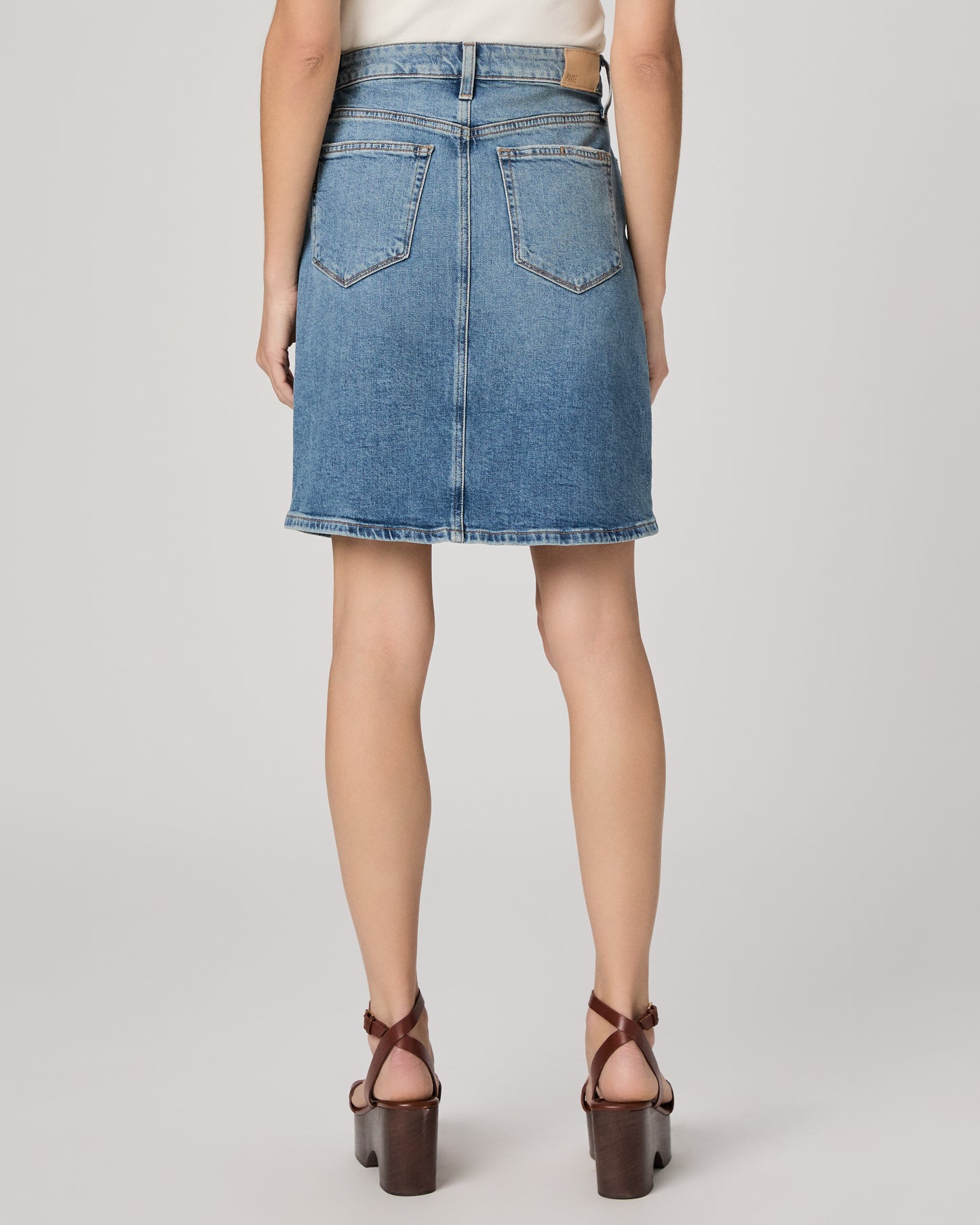 Person wearing a blue denim skirt on a plain background