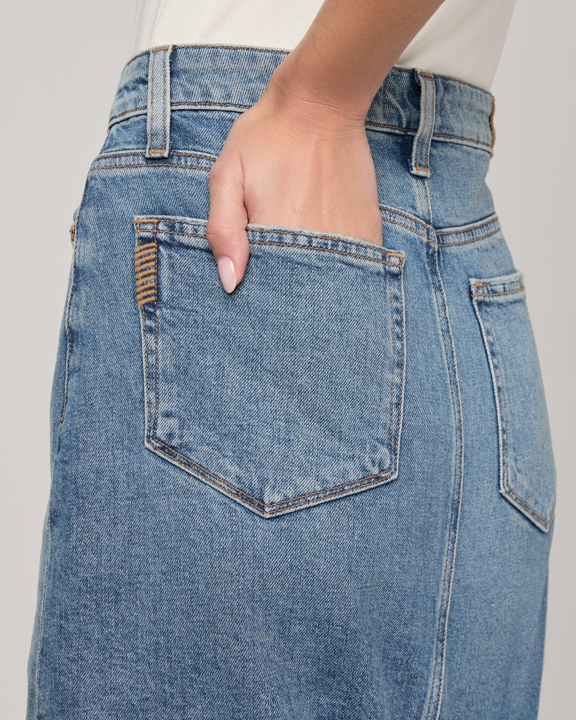 Close-up of a person wearing blue jeans with a plain background
