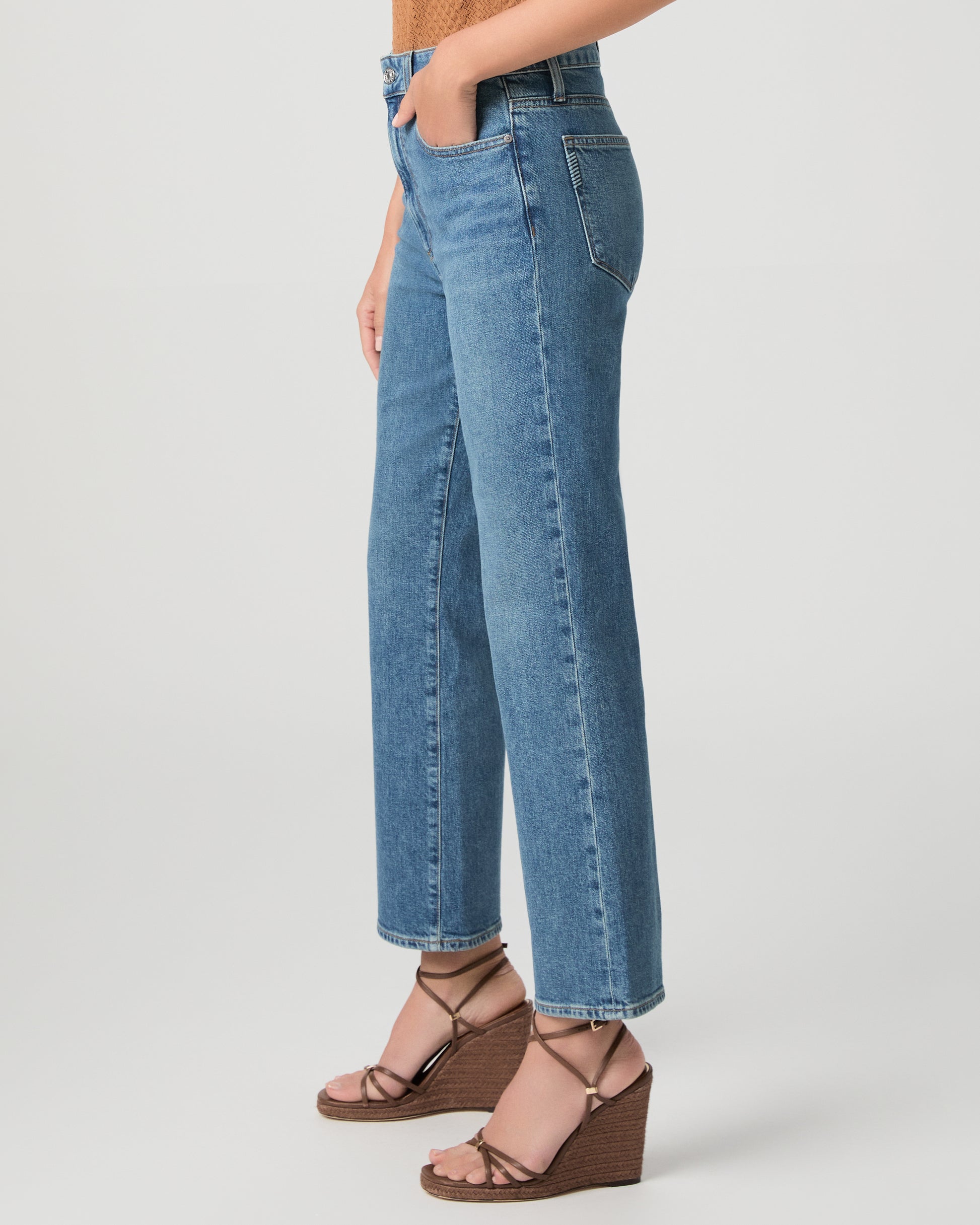 Women wearing a brown color top paired with medium wash denim and brown heels against a white background