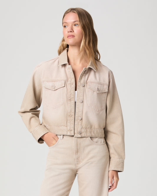Woman wearing a beige denim jacket on a plain background