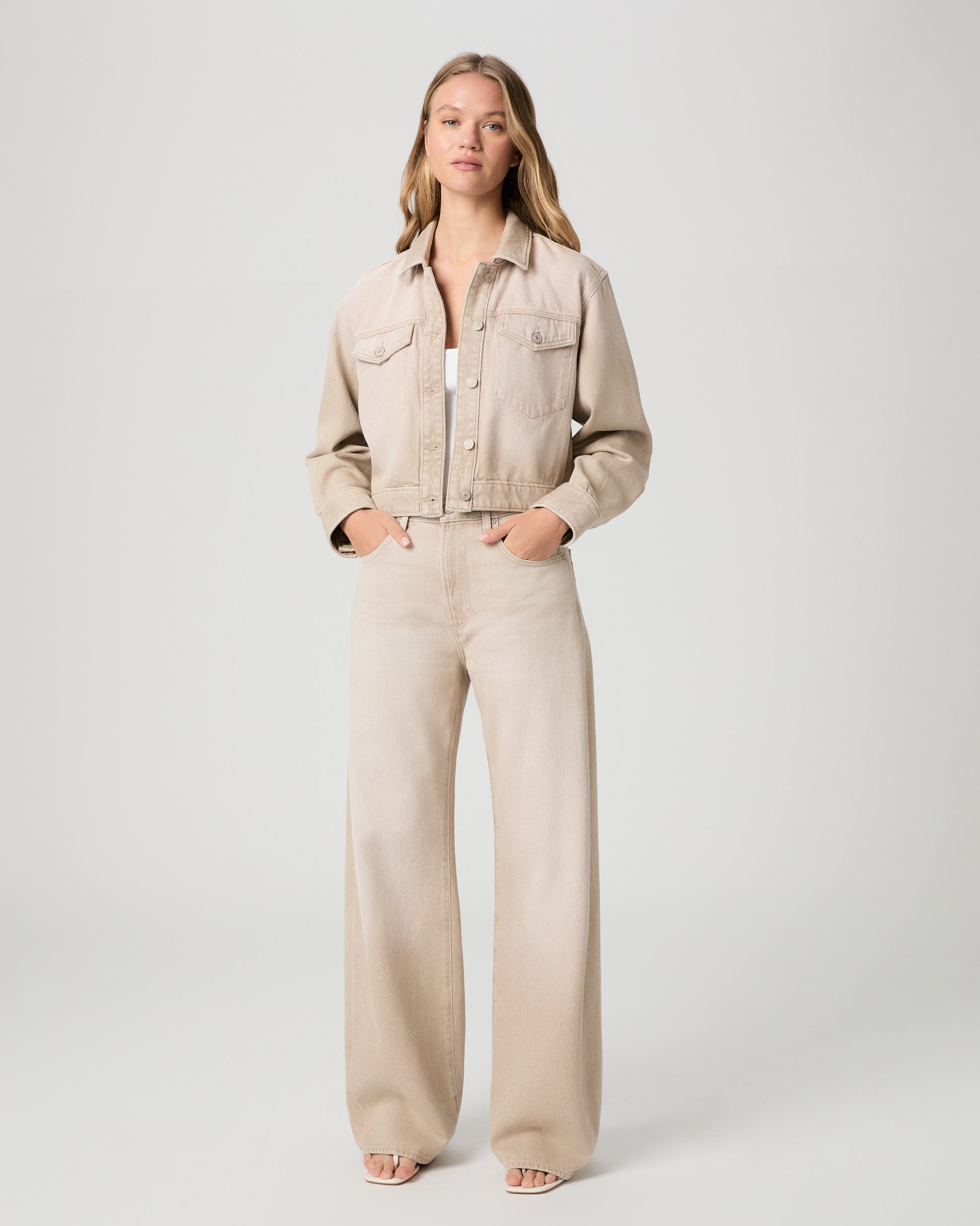 Woman wearing a beige jacket and pants on a white background