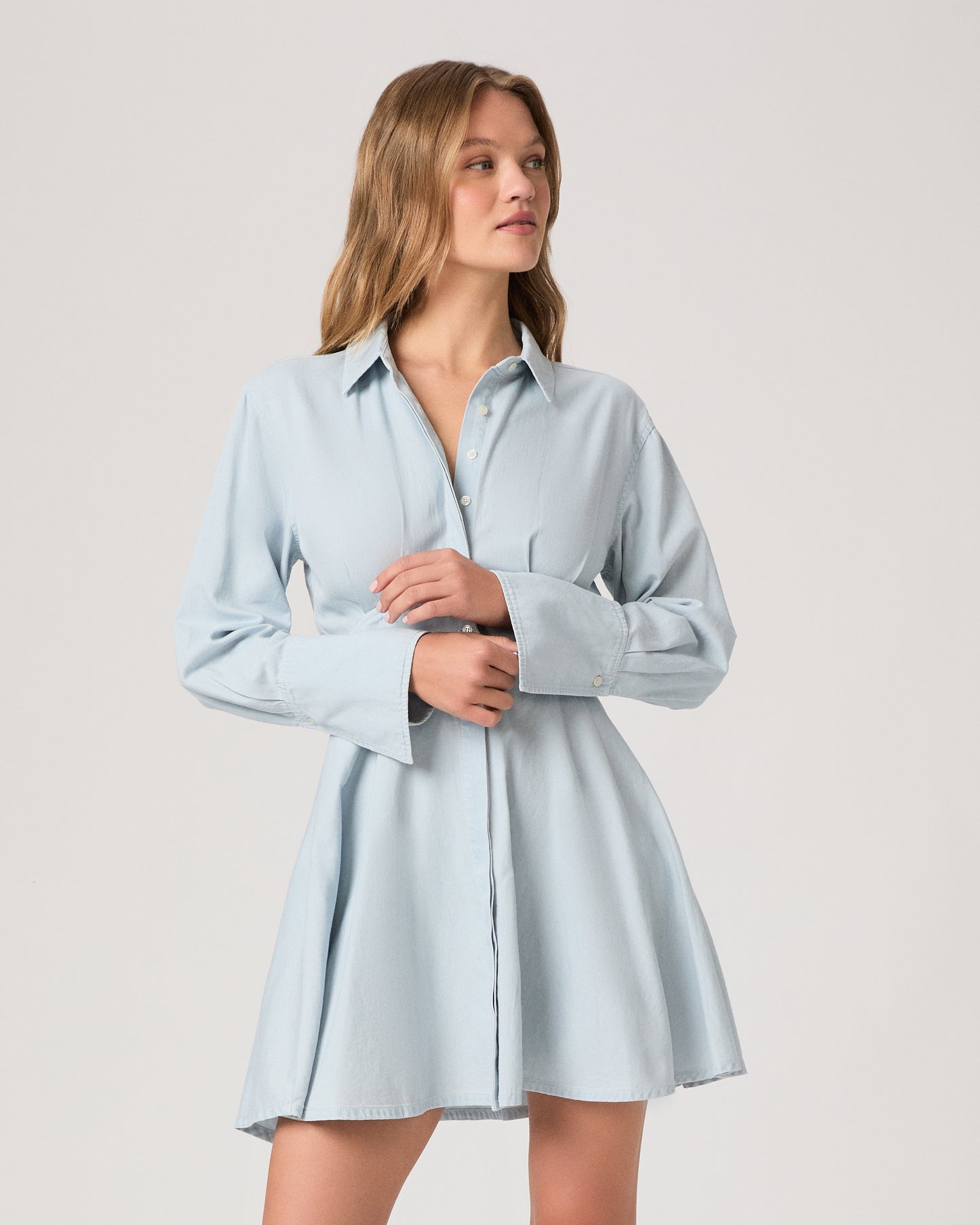 Woman wearing a light blue dress against a plain background