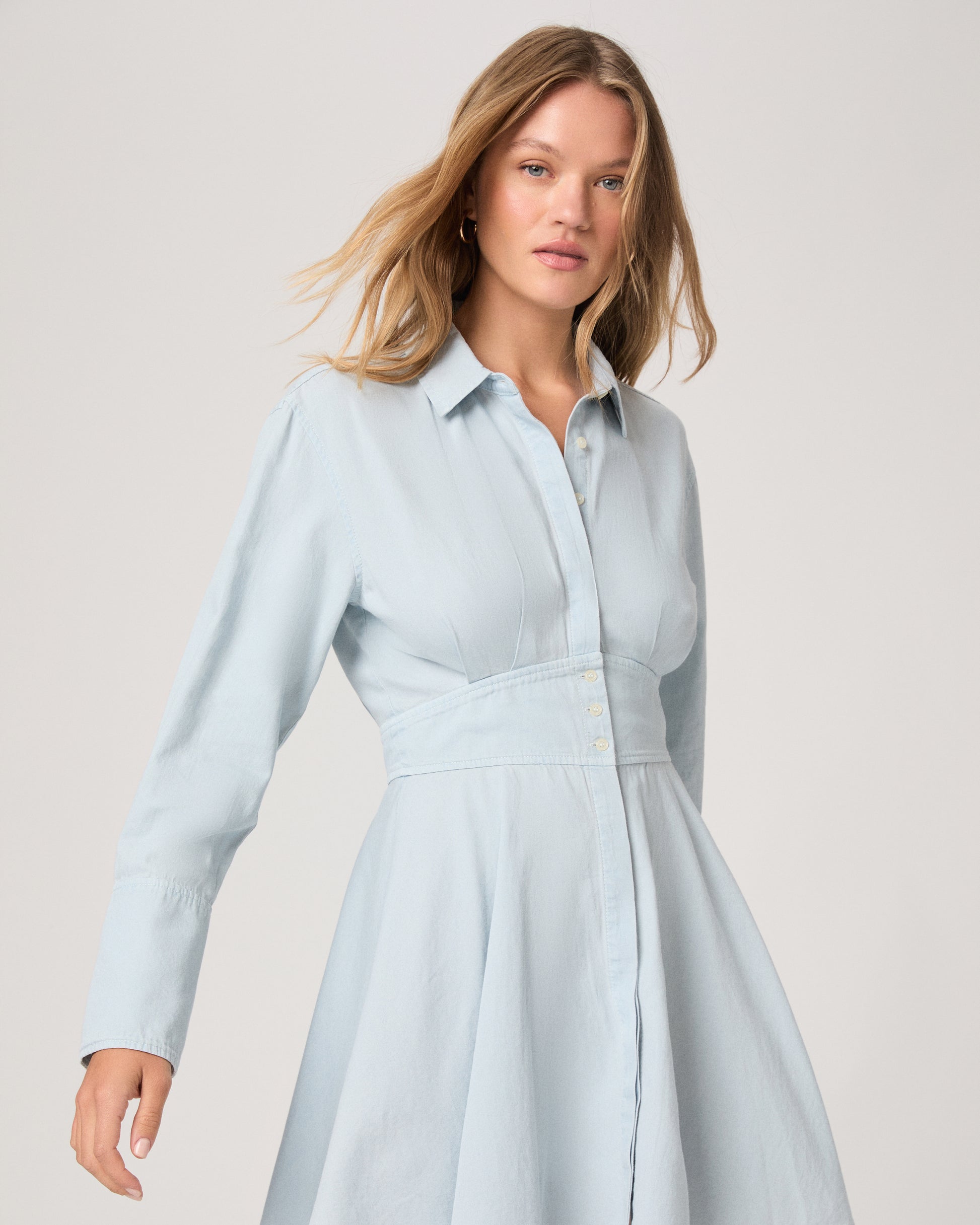 Woman wearing a light blue dress against a plain background
