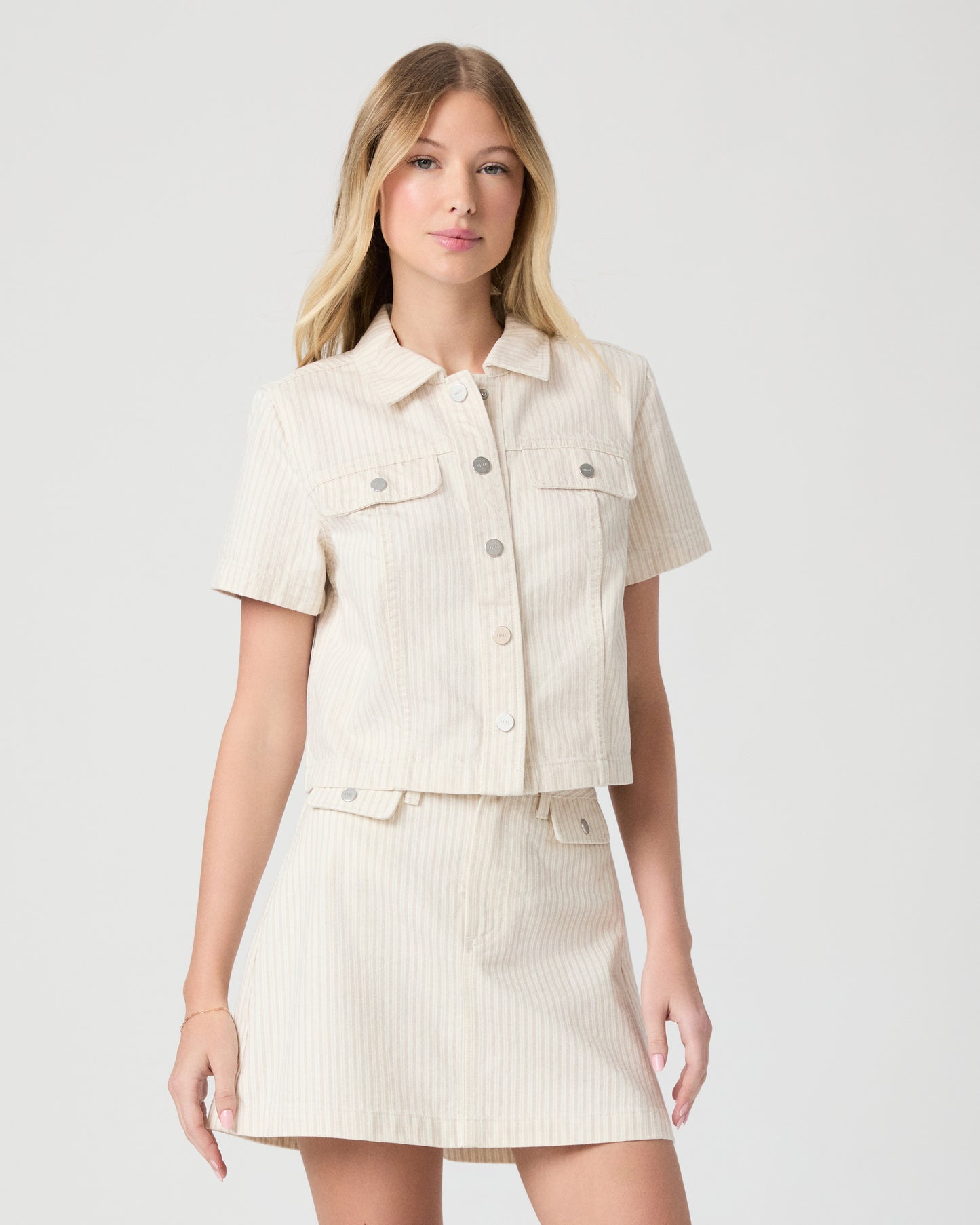 Woman wearing a cream-colored jacket and skirt on a white background