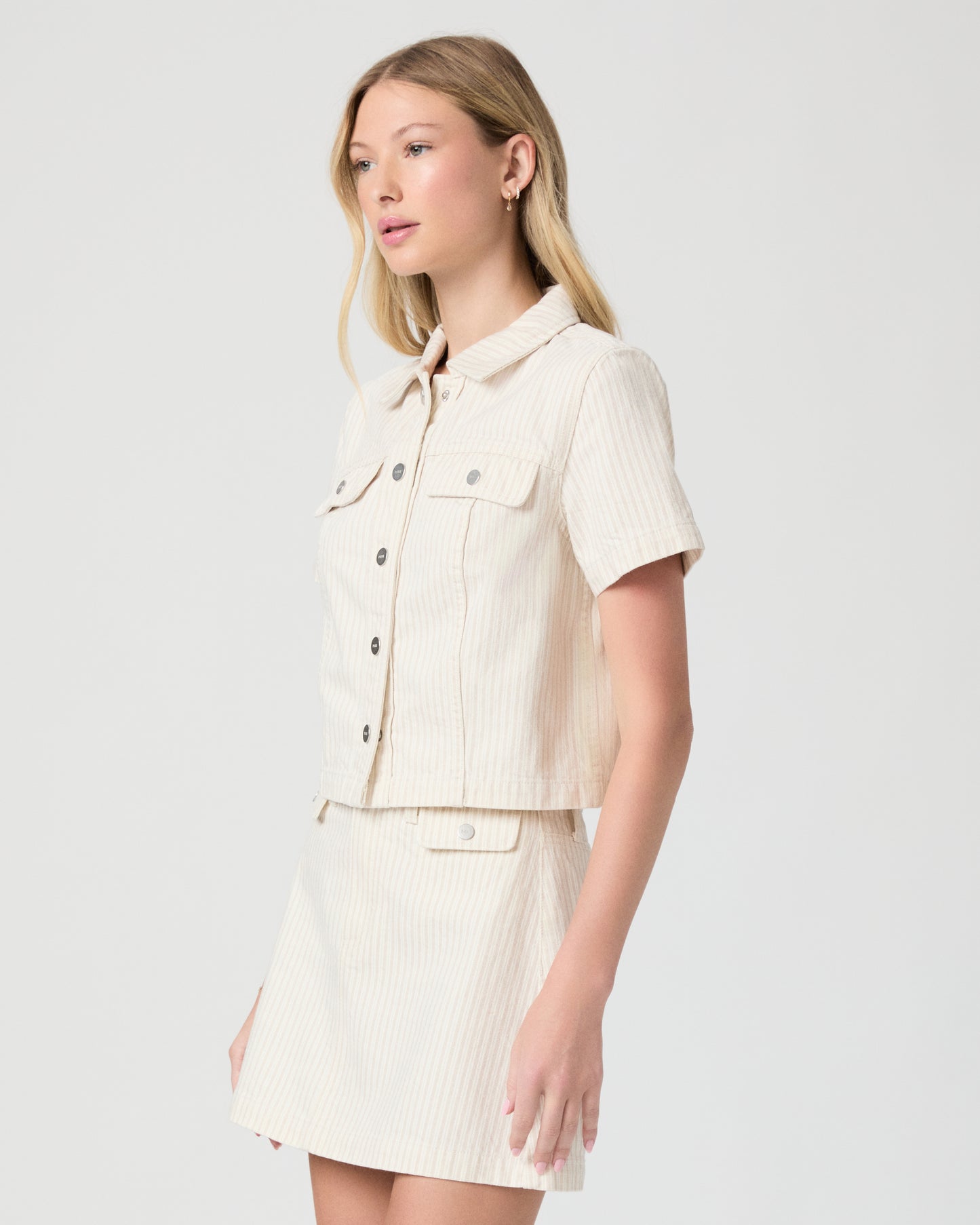 Woman wearing a cream-colored jacket and skirt on a white background