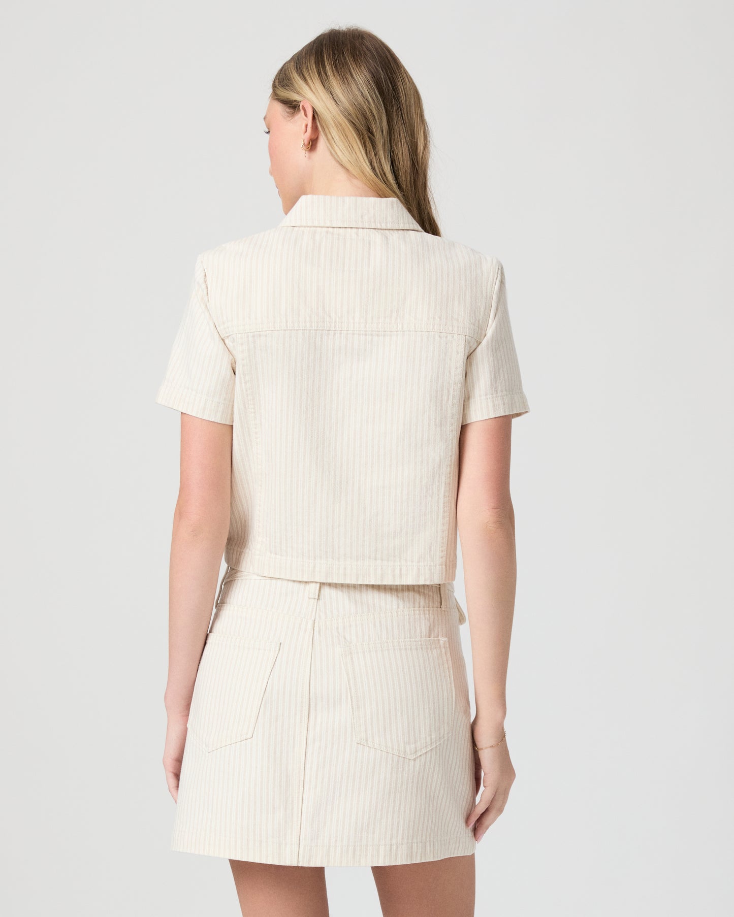 Woman wearing a cream-colored jacket and skirt on a white background