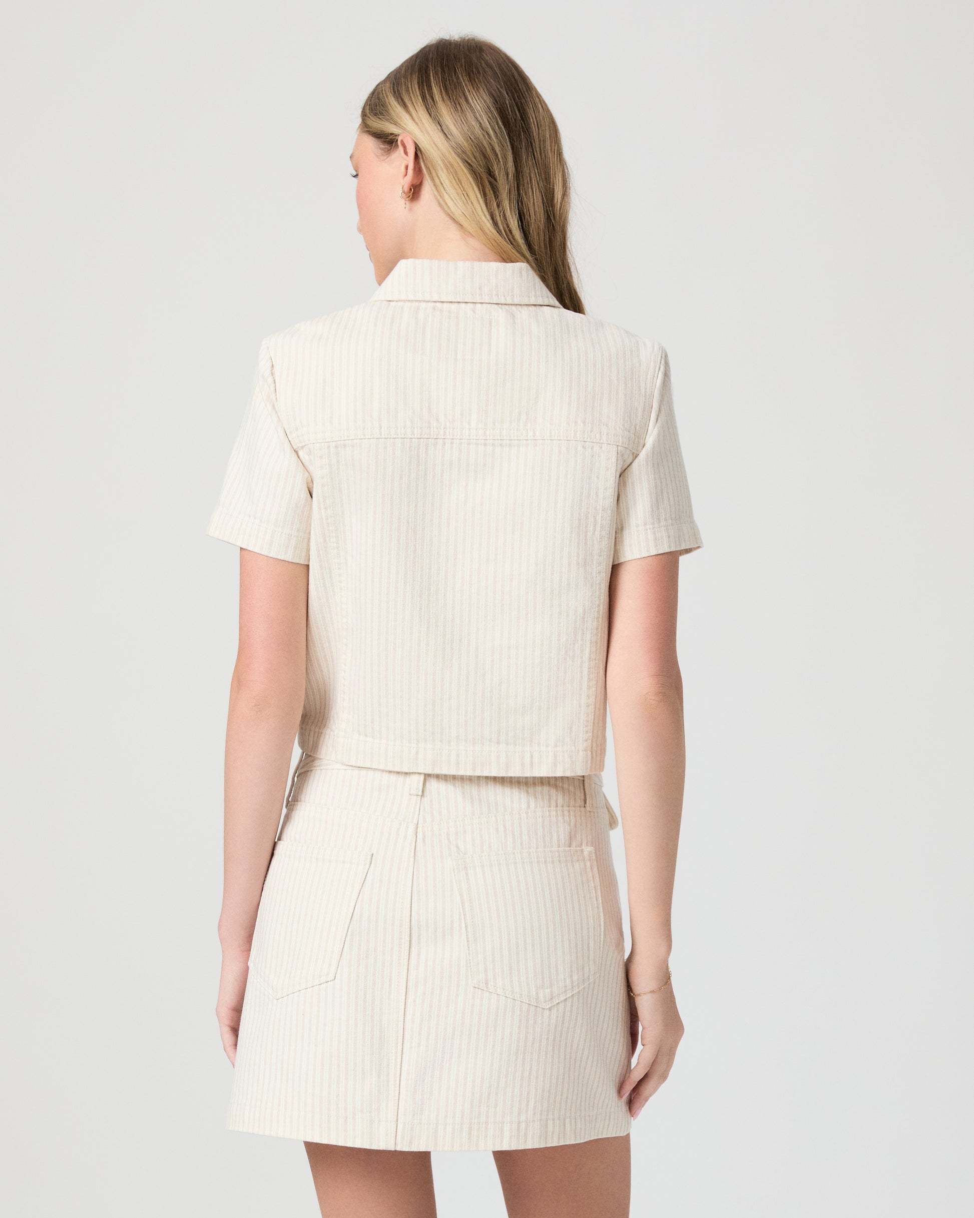 Woman wearing a cream-colored jacket and skirt on a white background