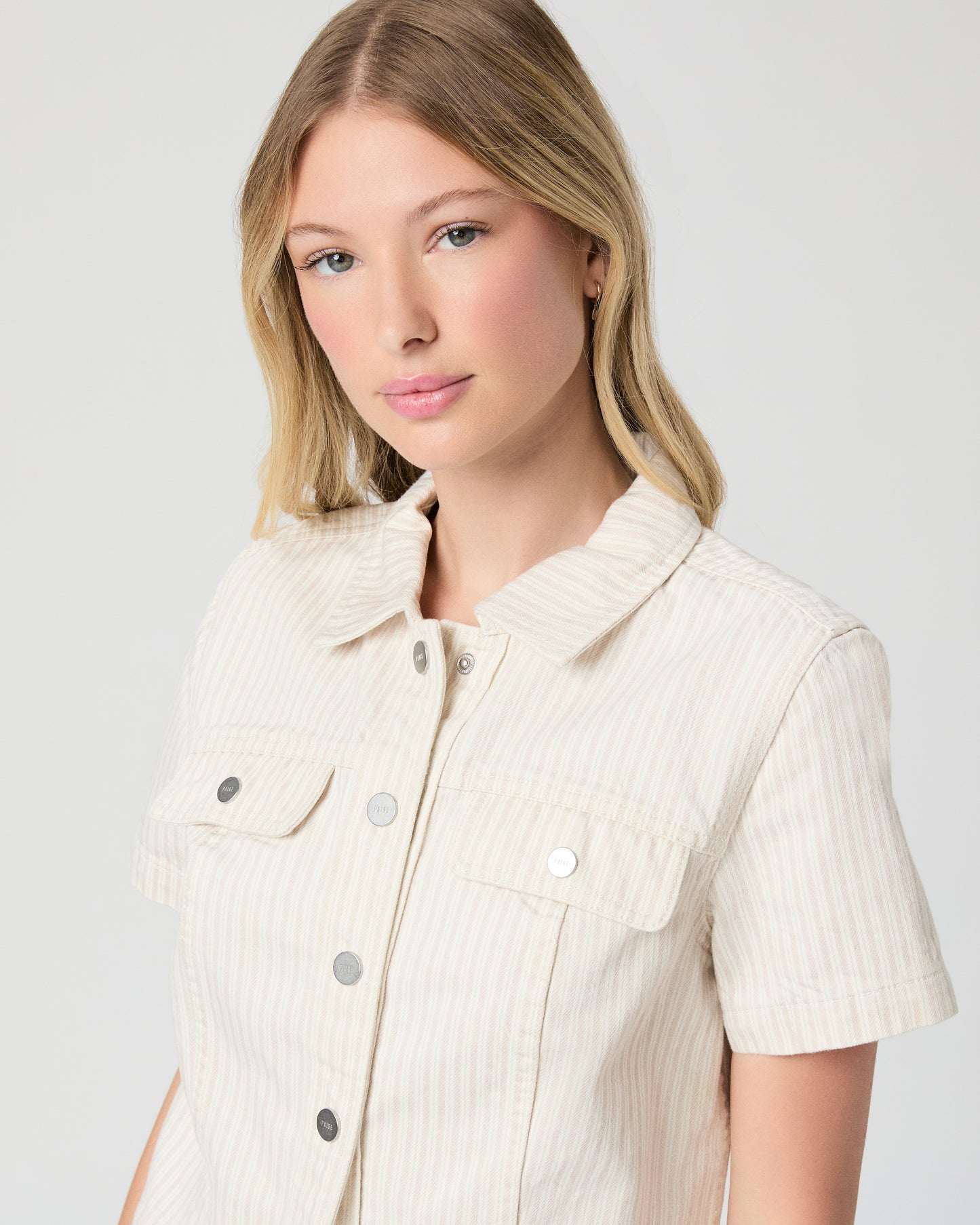 Woman wearing a cream-colored jacket and skirt on a white background