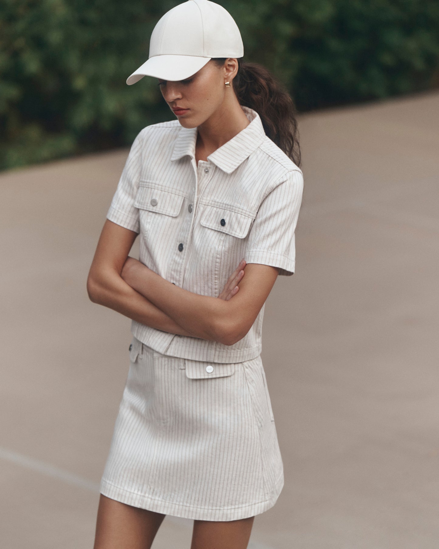 Woman wearing a light-colored outfit with a cap in an outdoor setting