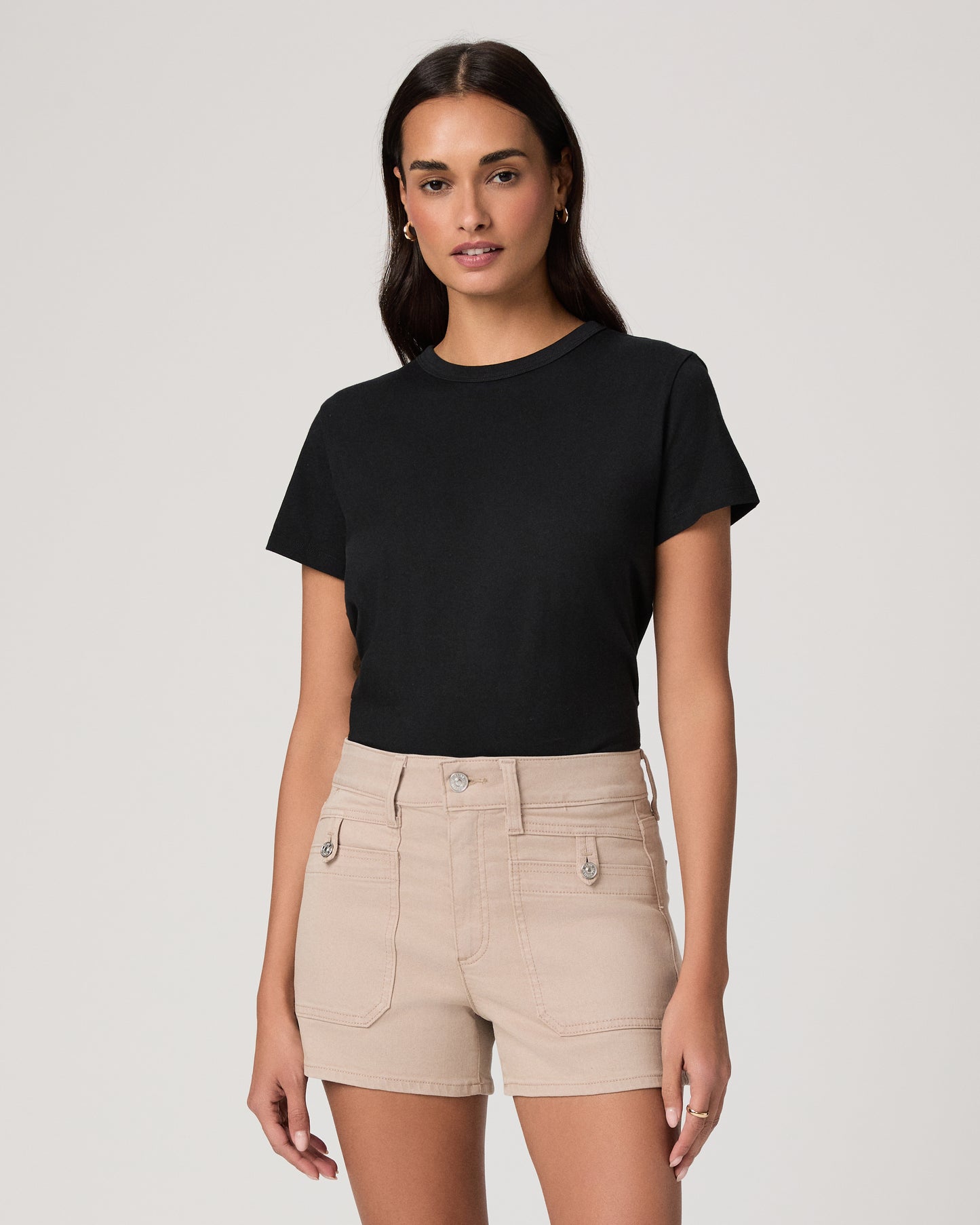 Woman wearing a black t-shirt and beige shorts on a white background