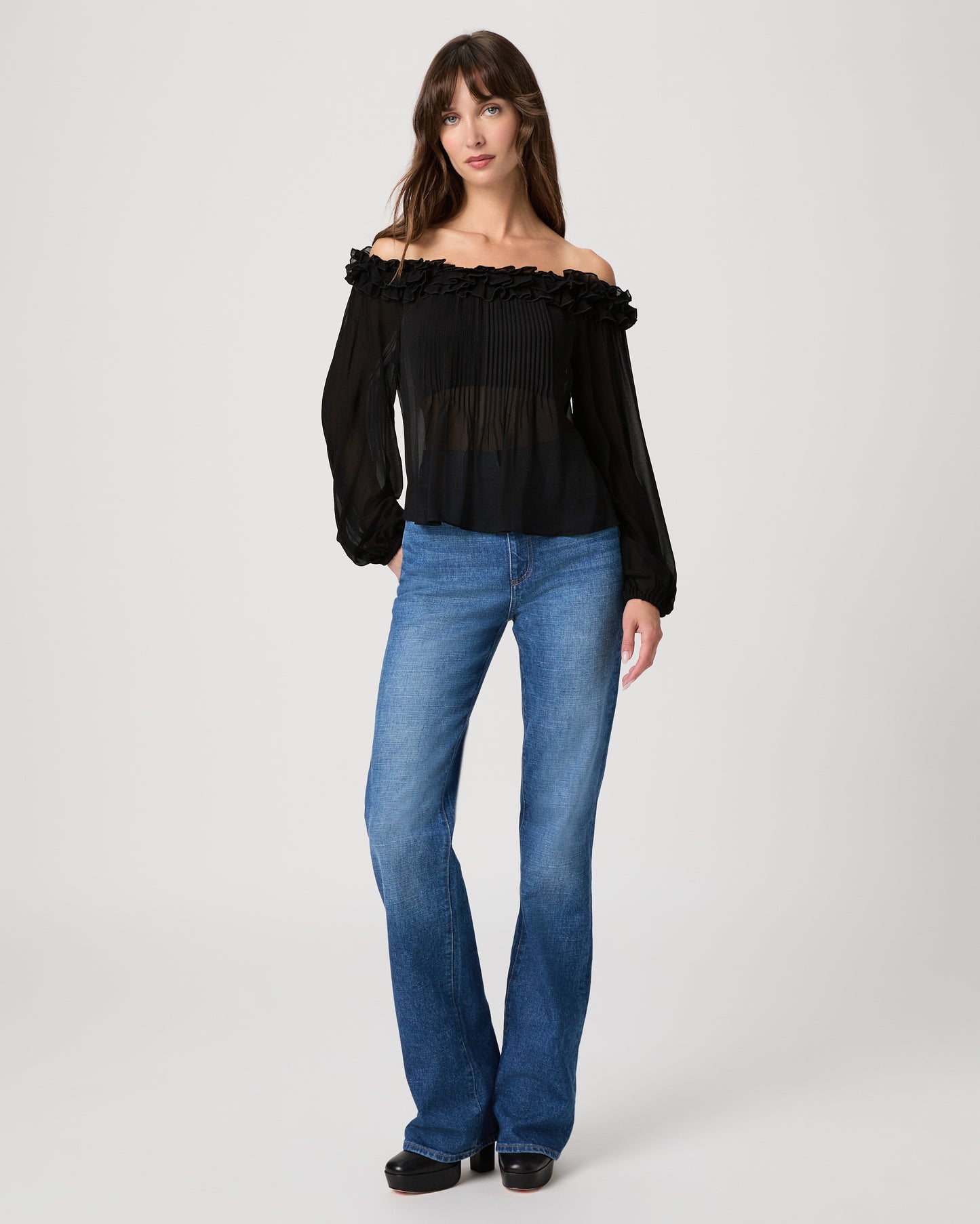 Women wearing a black sleeveless top paired with medium wash jeans on a white background