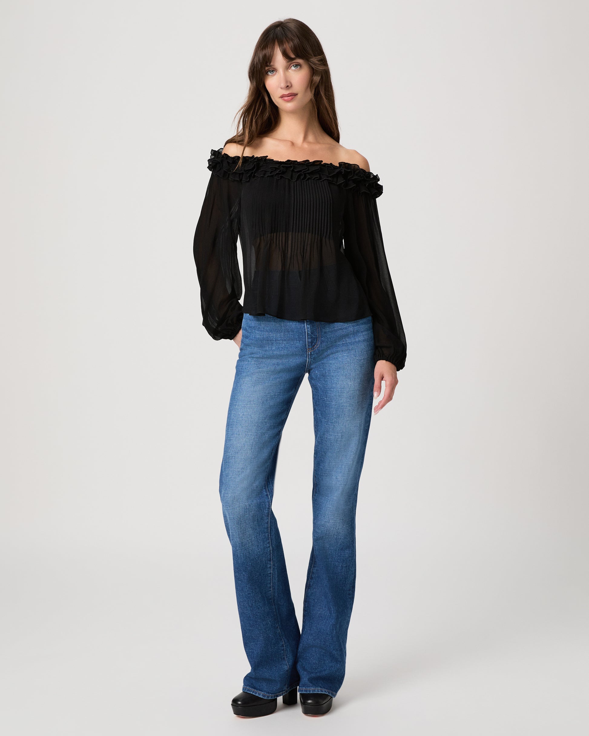 Women wearing a black sleeveless top paired with medium wash jeans on a white background