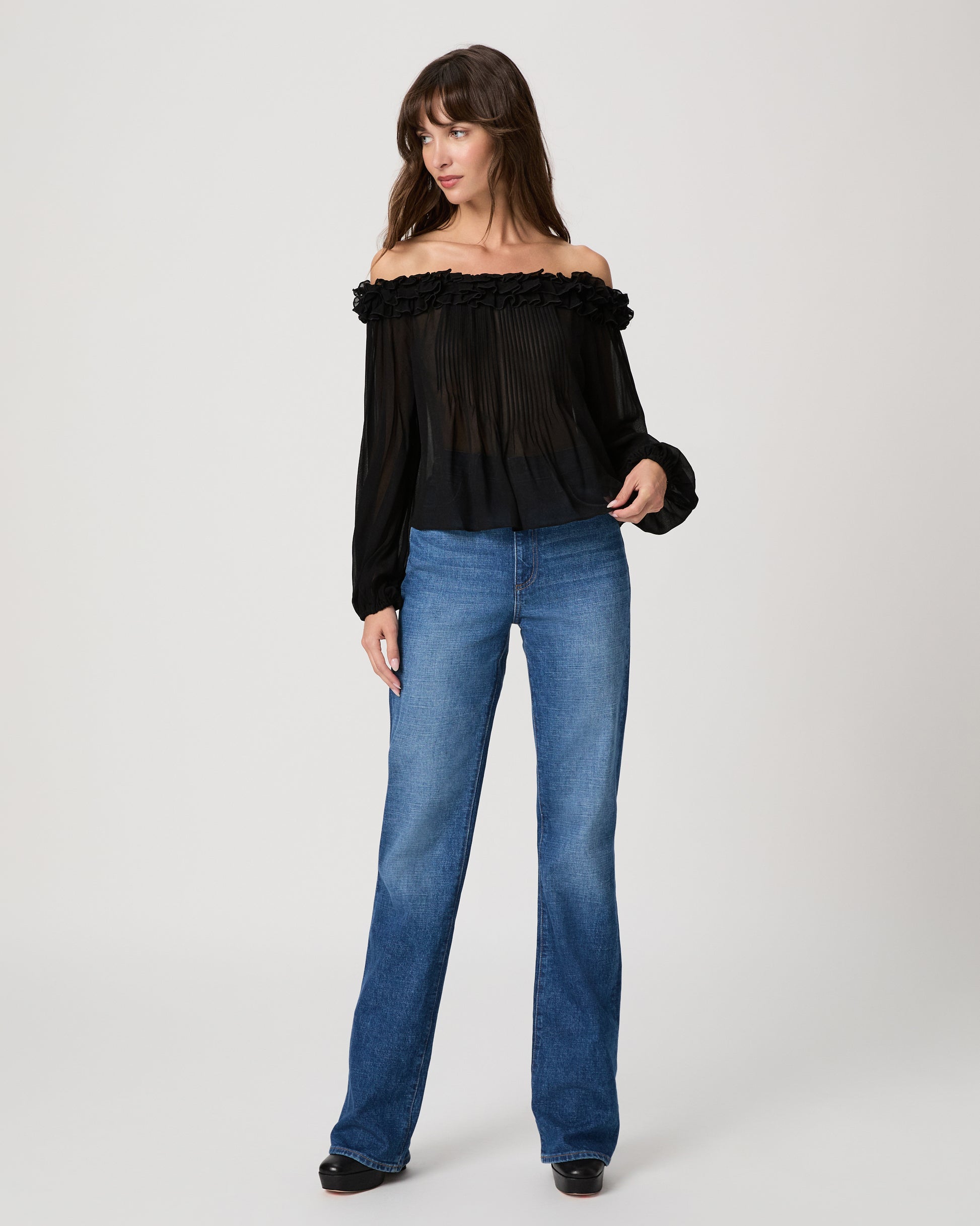 Women wearing a black sleeveless top paired with medium wash jeans on a white background