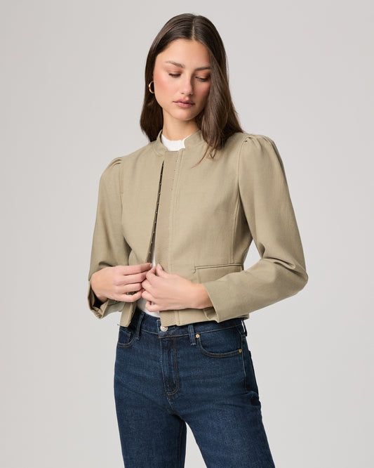 Woman wearing a light green jacket and dark blue jeans on a white background