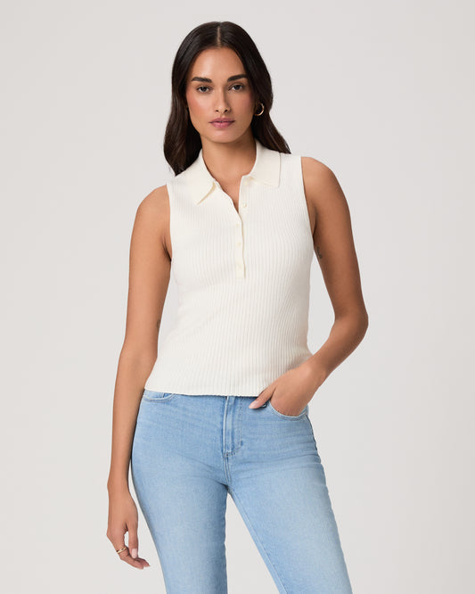 Woman wearing a white sleeveless shirt and light jeans against a white background
