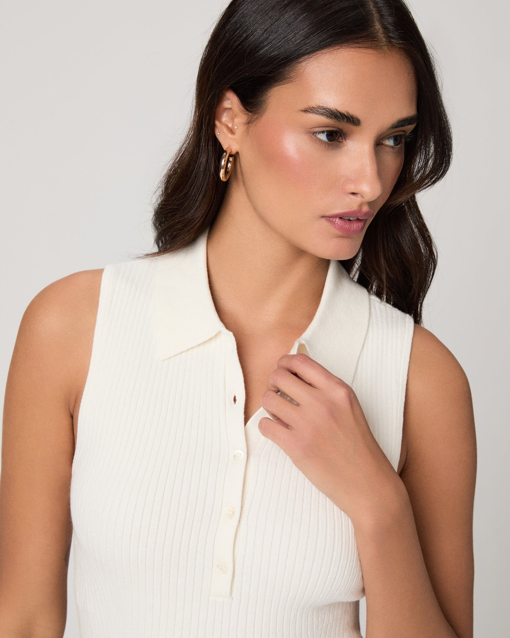 Woman wearing a white sleeveless shirt against a white background