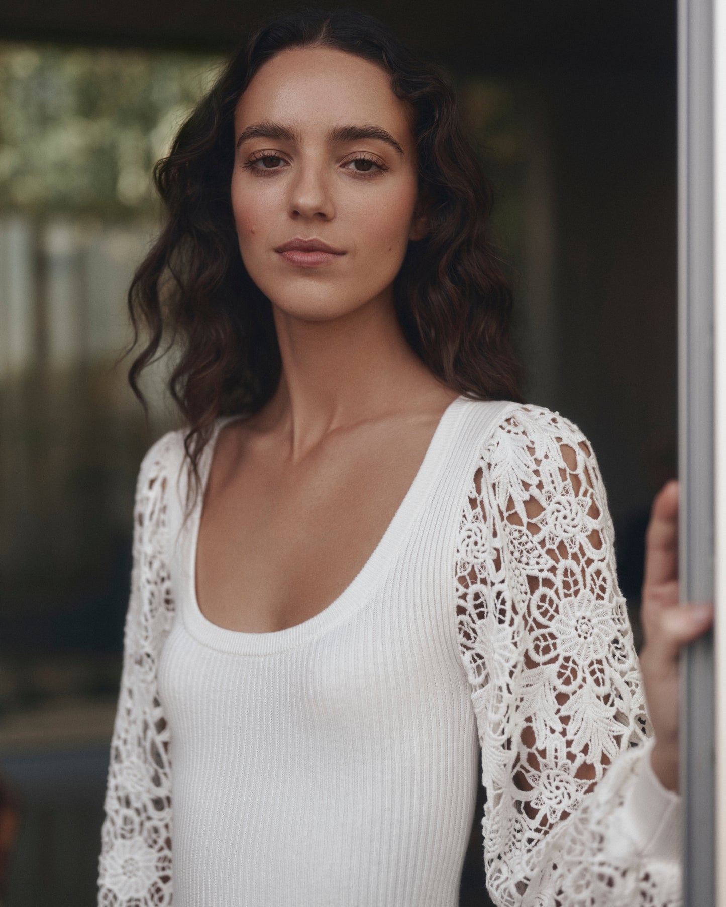 Woman wearing a white dress with lace sleeves in an indoor setting