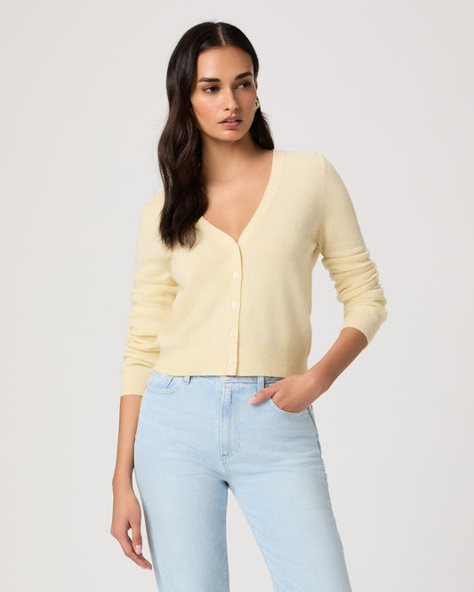 Woman wearing a light yellow cardigan and light blue jeans on a white background