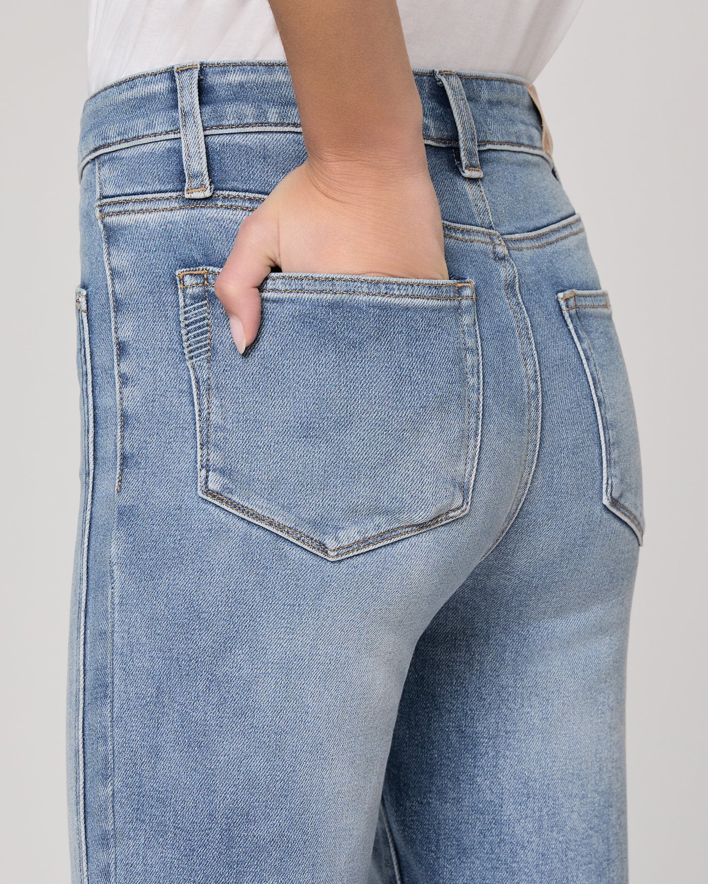 Woman wearing a white blouse and blue jeans on a plain background