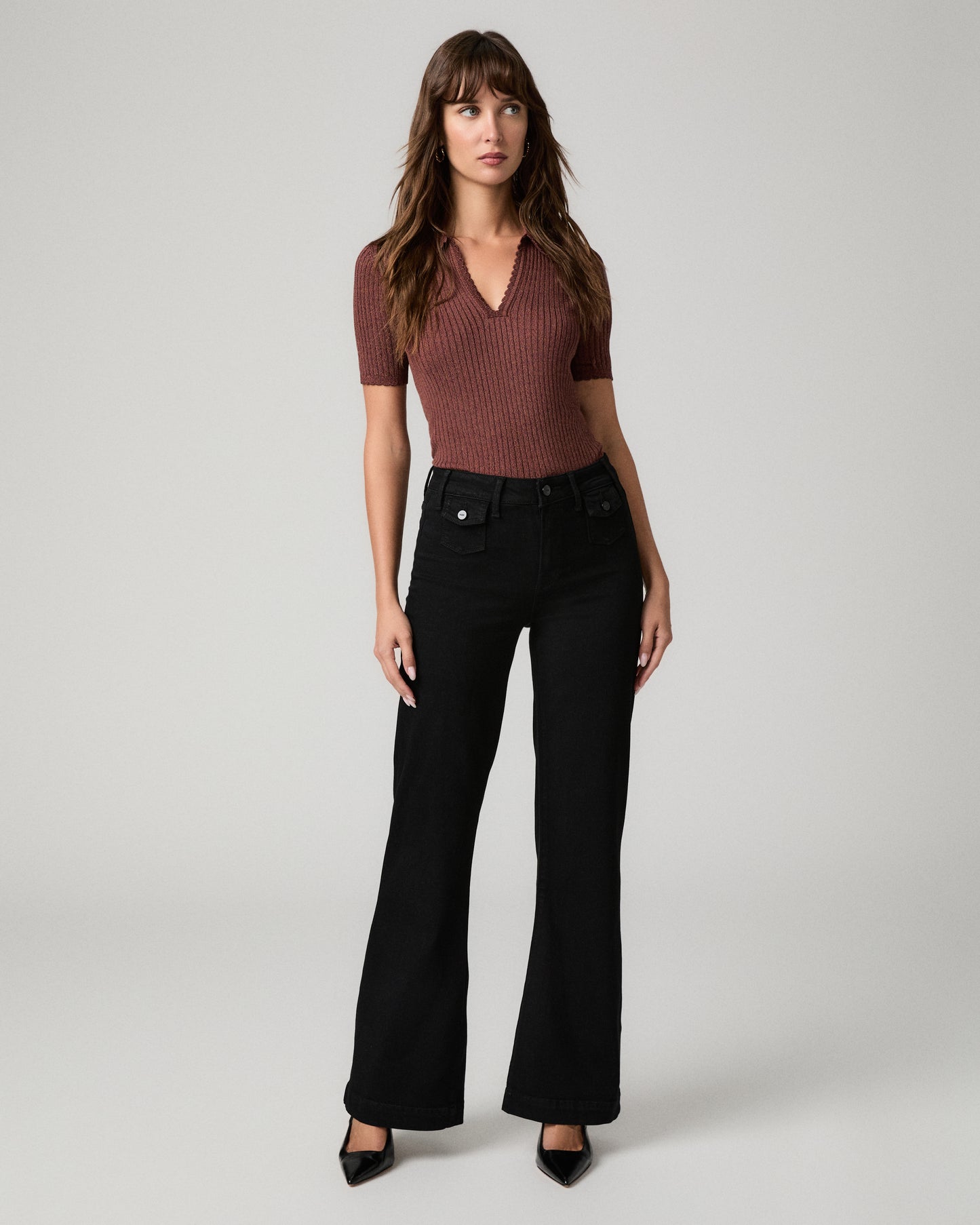Women wearing burgundy shirt and black pants paired with black heels against a white background
