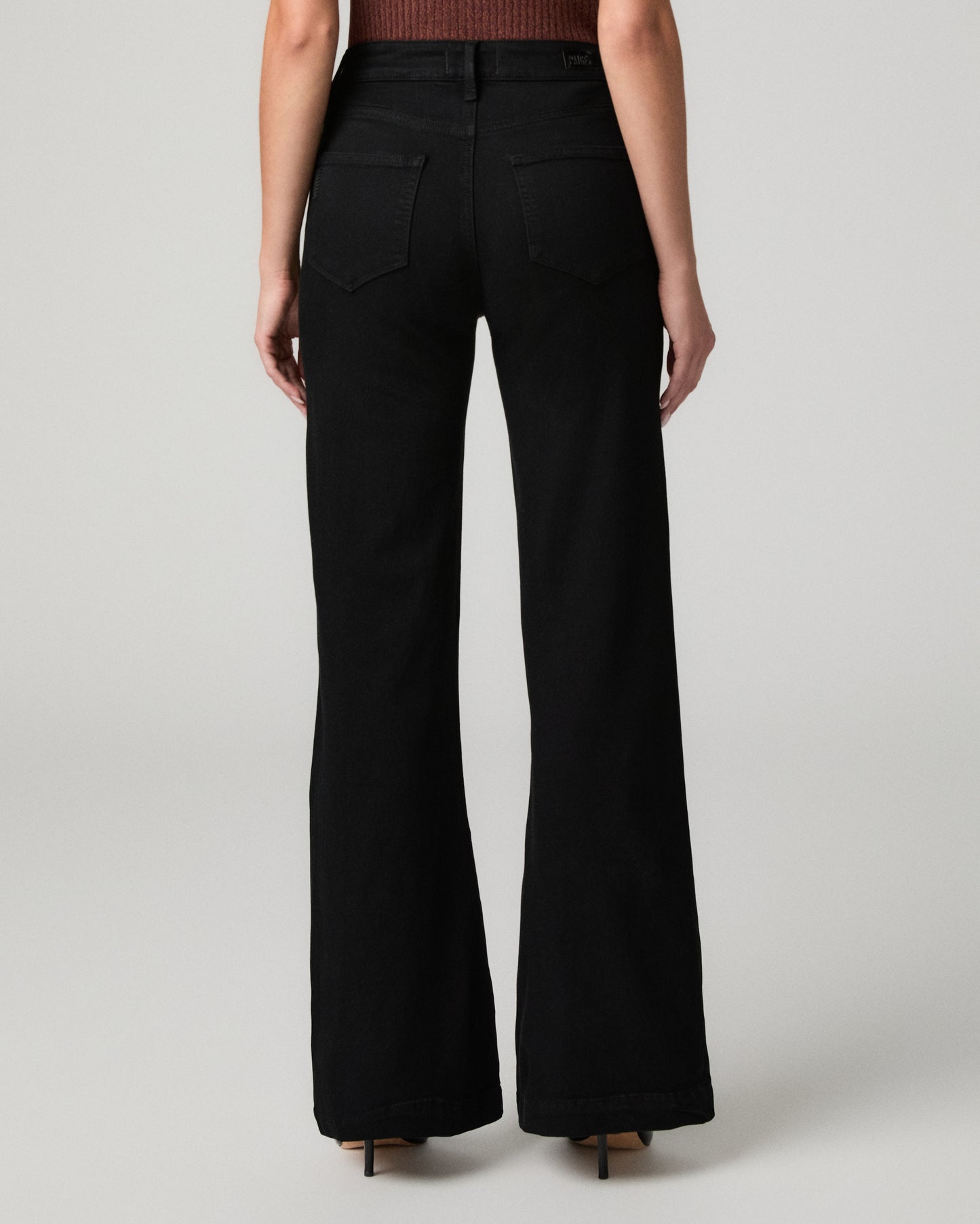 Women wearing burgundy shirt and black pants paired with black heels against a white background