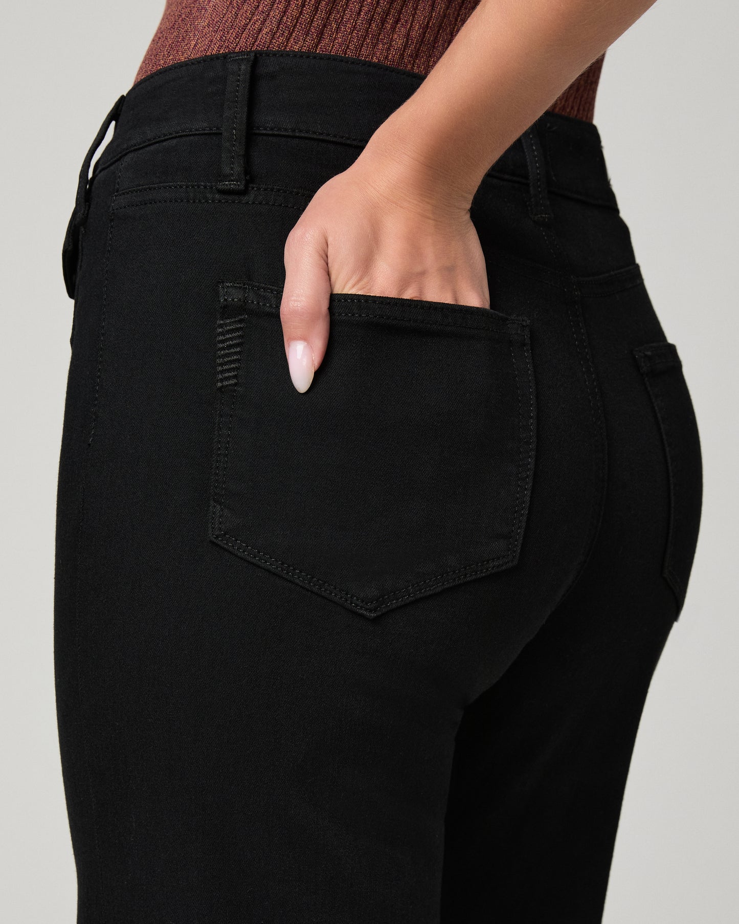 Women wearing burgundy shirt and black pants paired with black heels against a white background