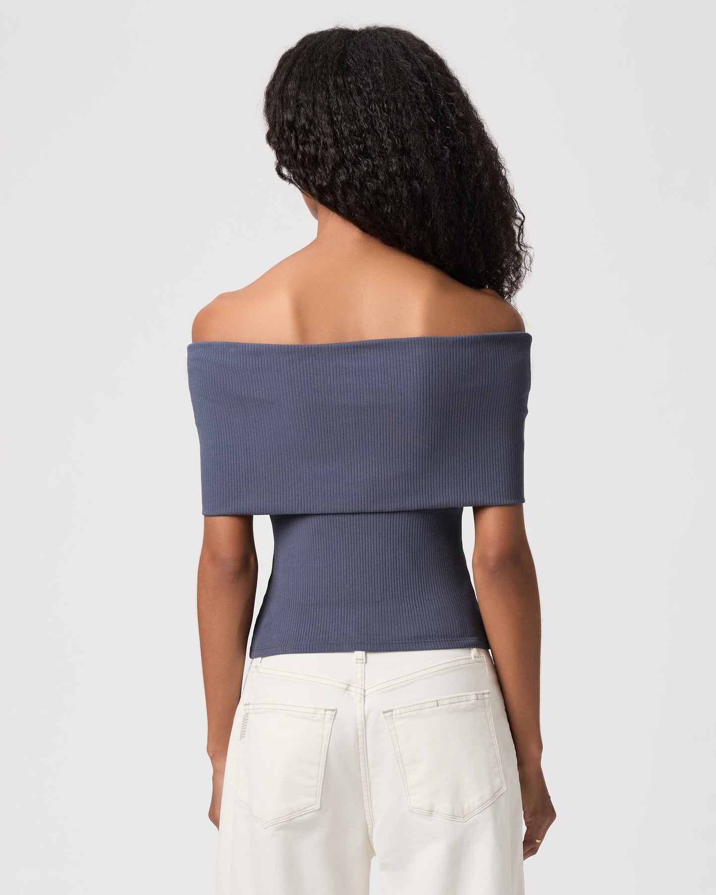 women wearing a blue off the shoulder top paired with white jeans against a white background 