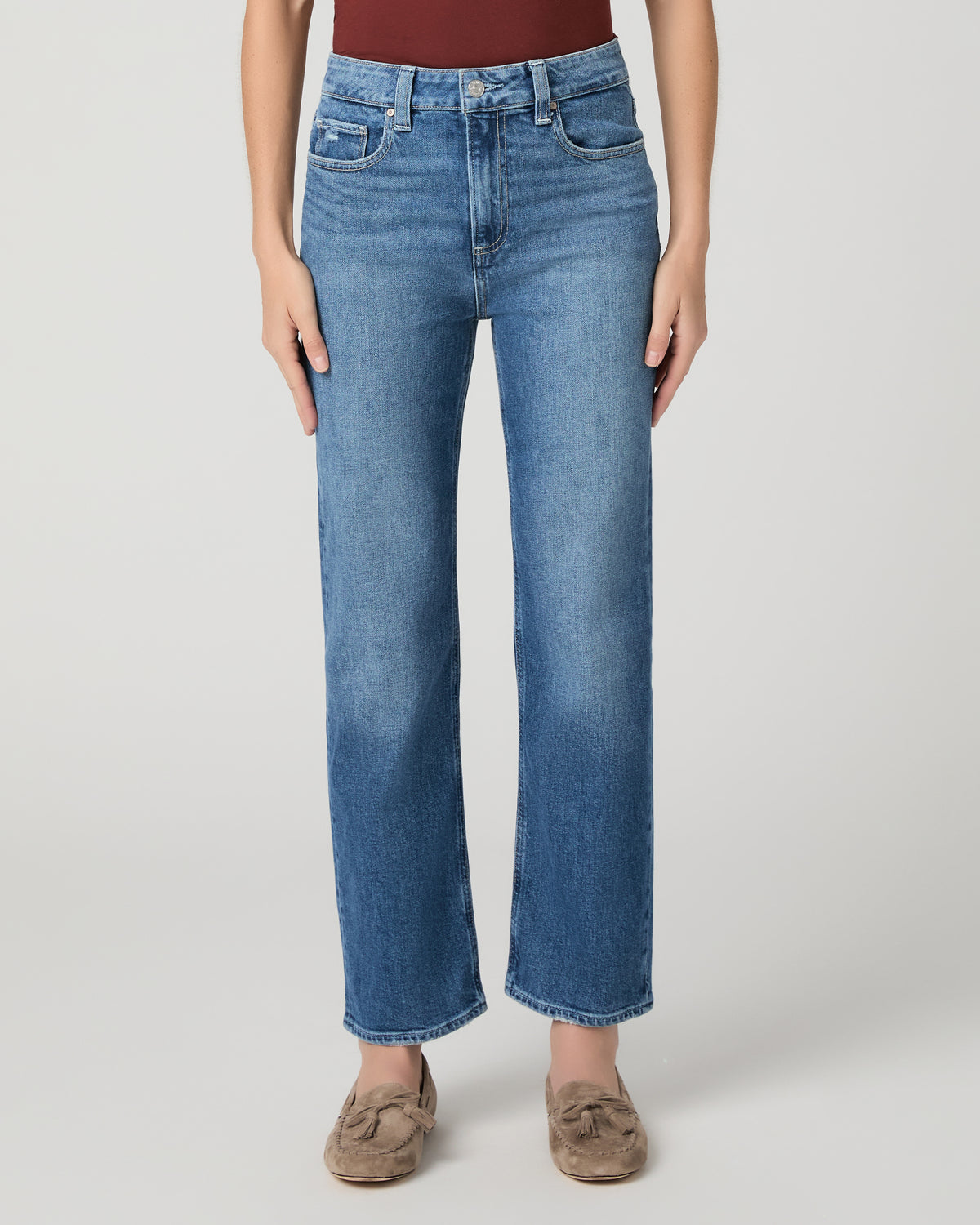 Women wearing red tee and blue jeans paired with brown flats against a white background