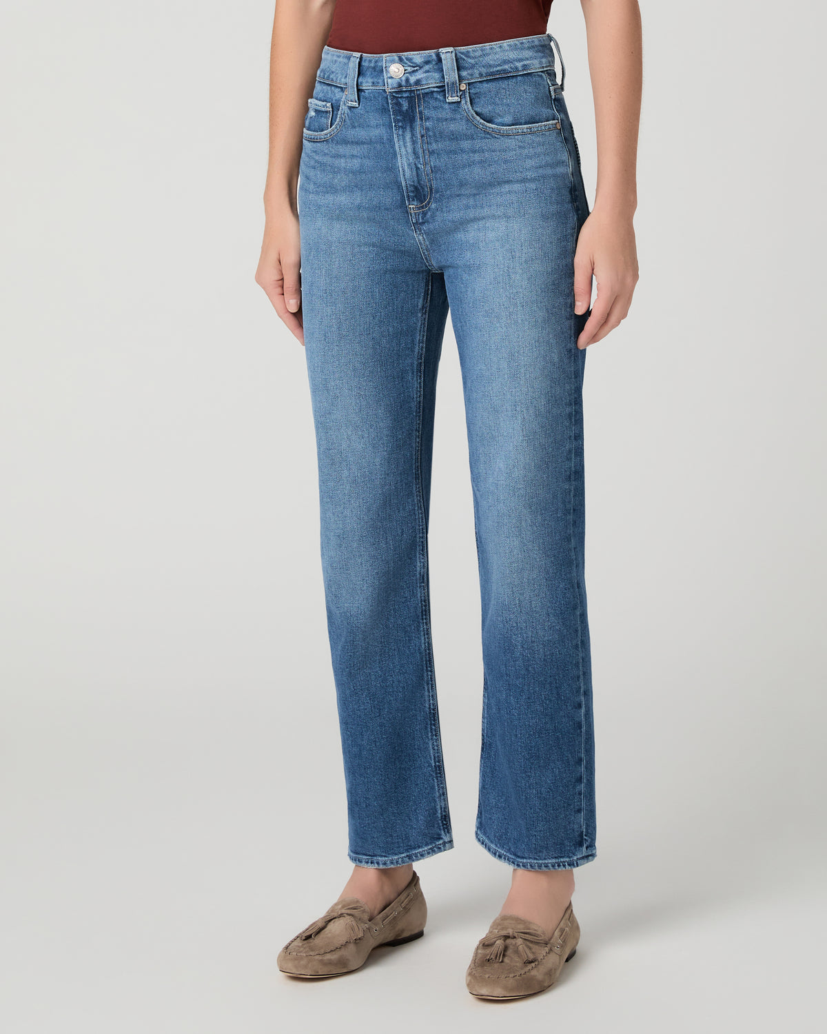 Women wearing red tee and blue jeans paired with brown flats against a white background