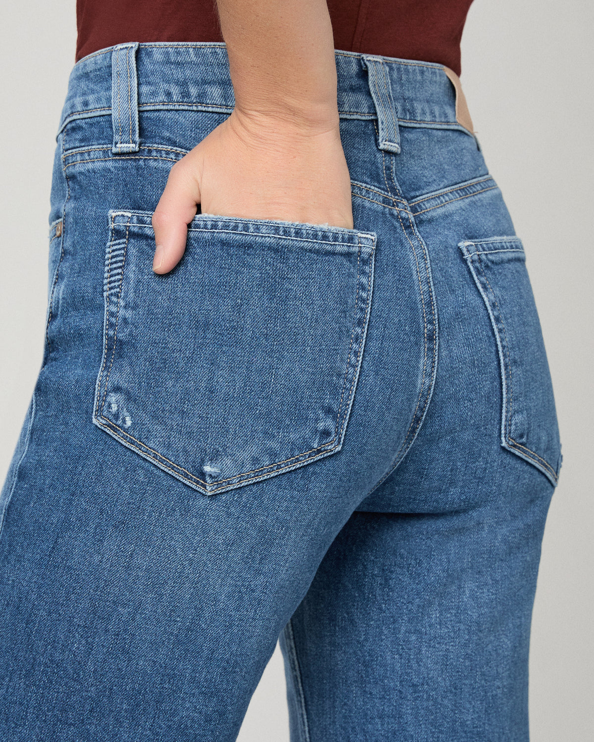 Women wearing red tee and blue jeans paired with brown flats against a white background