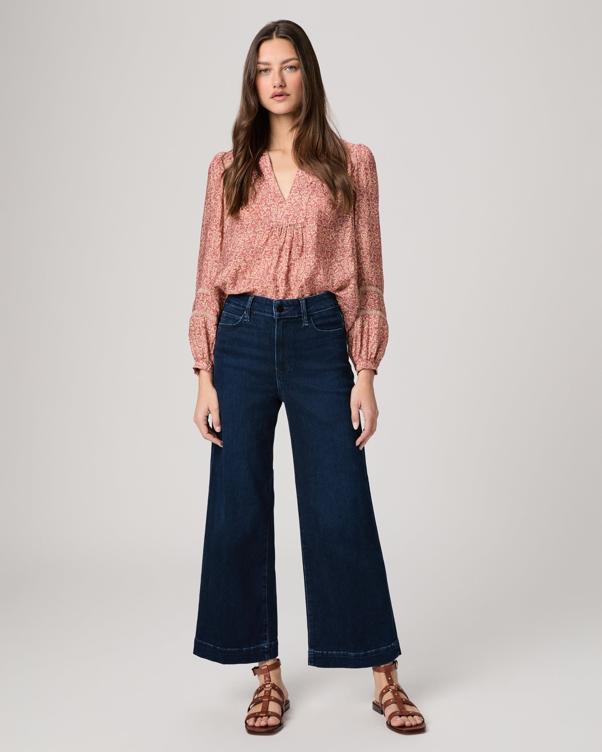 Woman wearing a pink blouse and dark blue jeans on a white background
