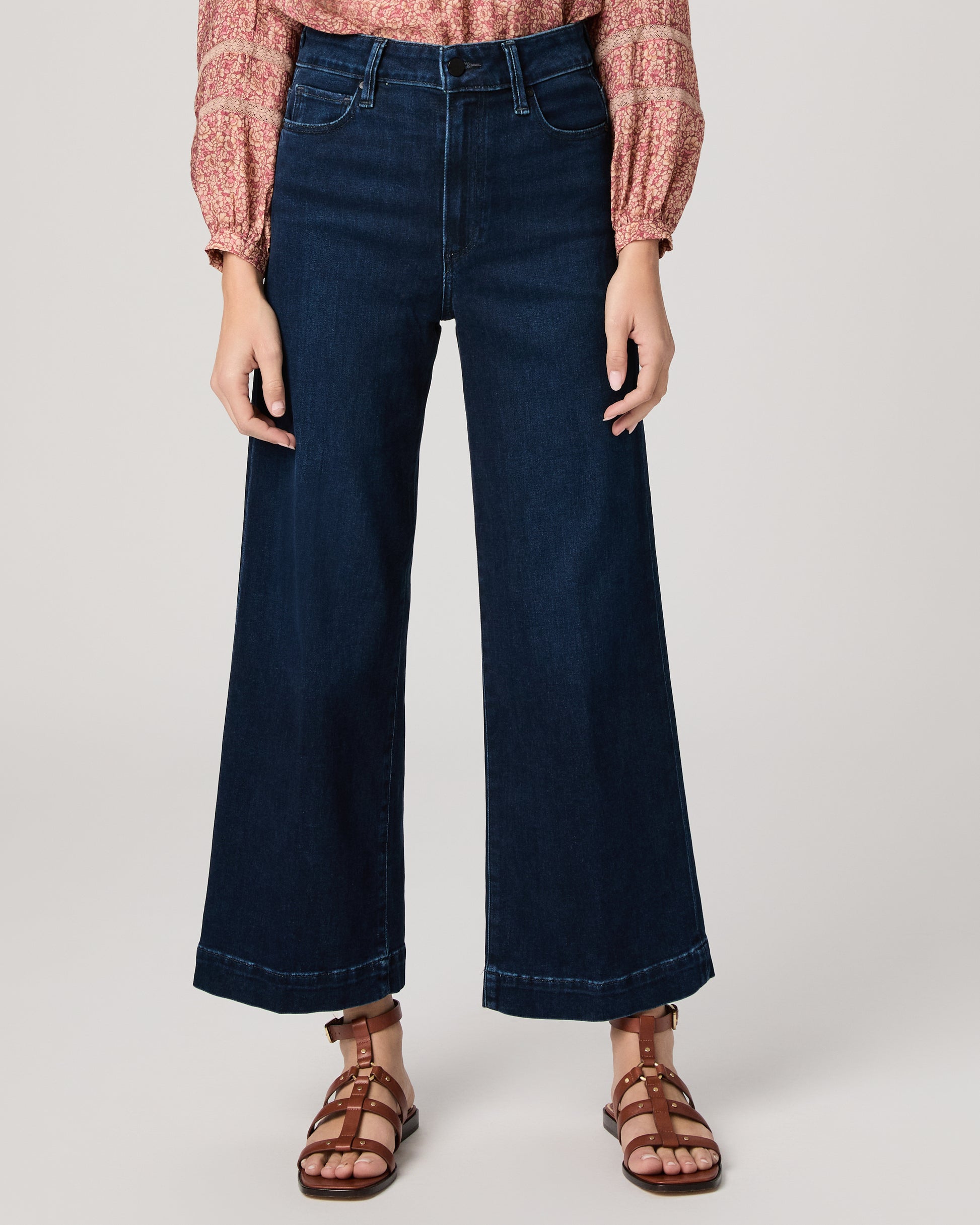 Woman wearing a pink blouse and dark blue jeans on a white background