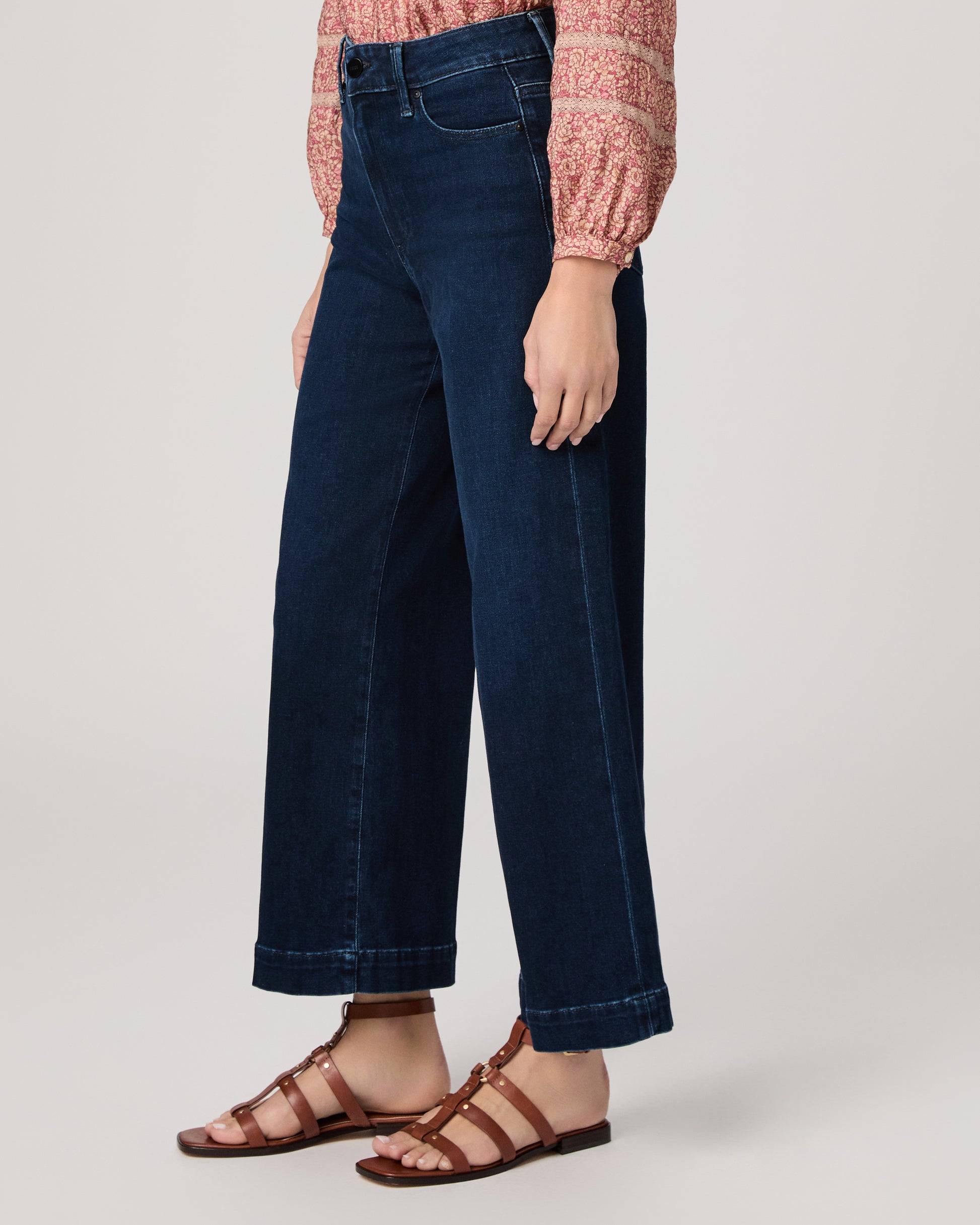 Woman wearing a pink blouse and dark blue jeans on a white background