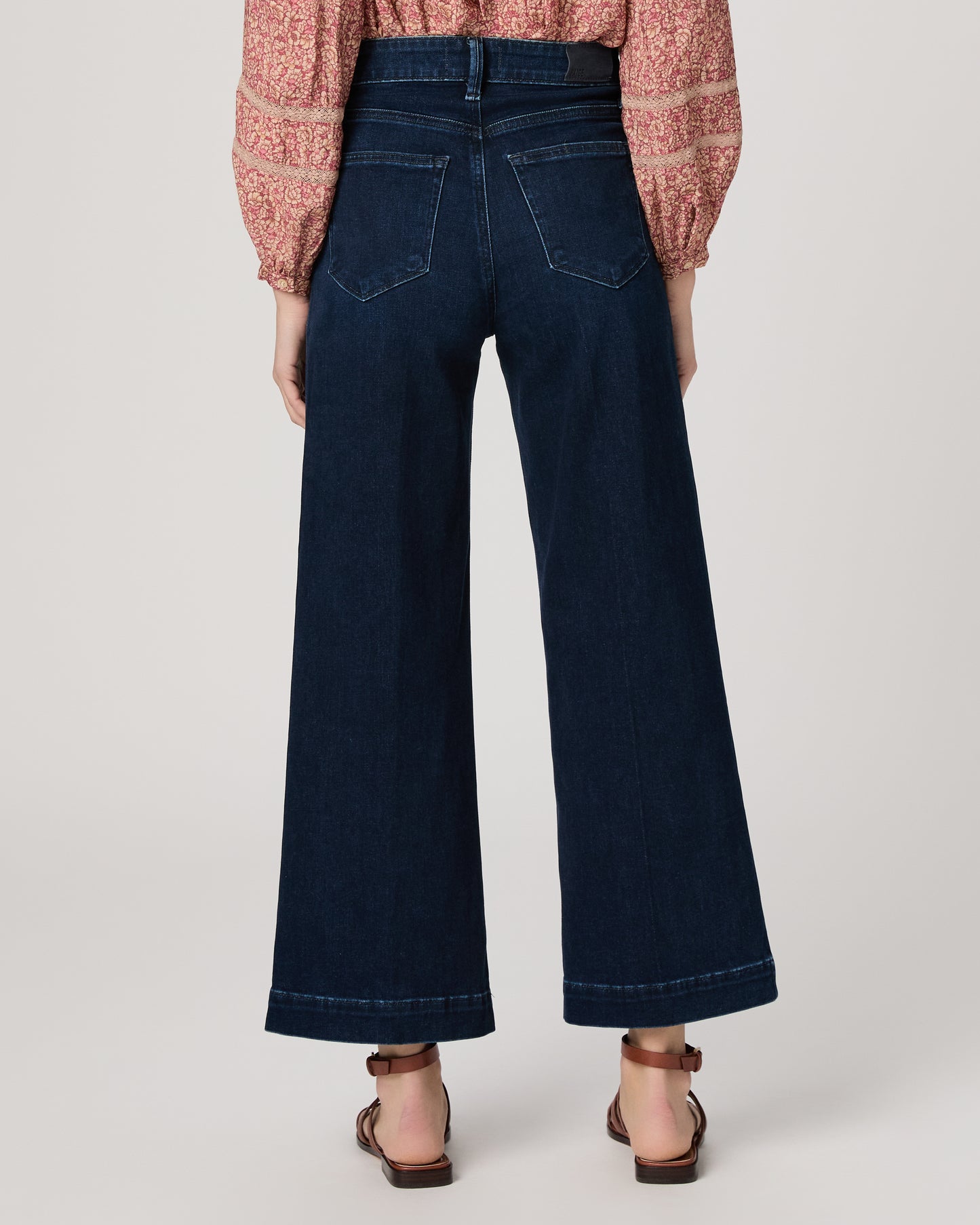 Woman wearing a pink blouse and dark blue jeans on a white background