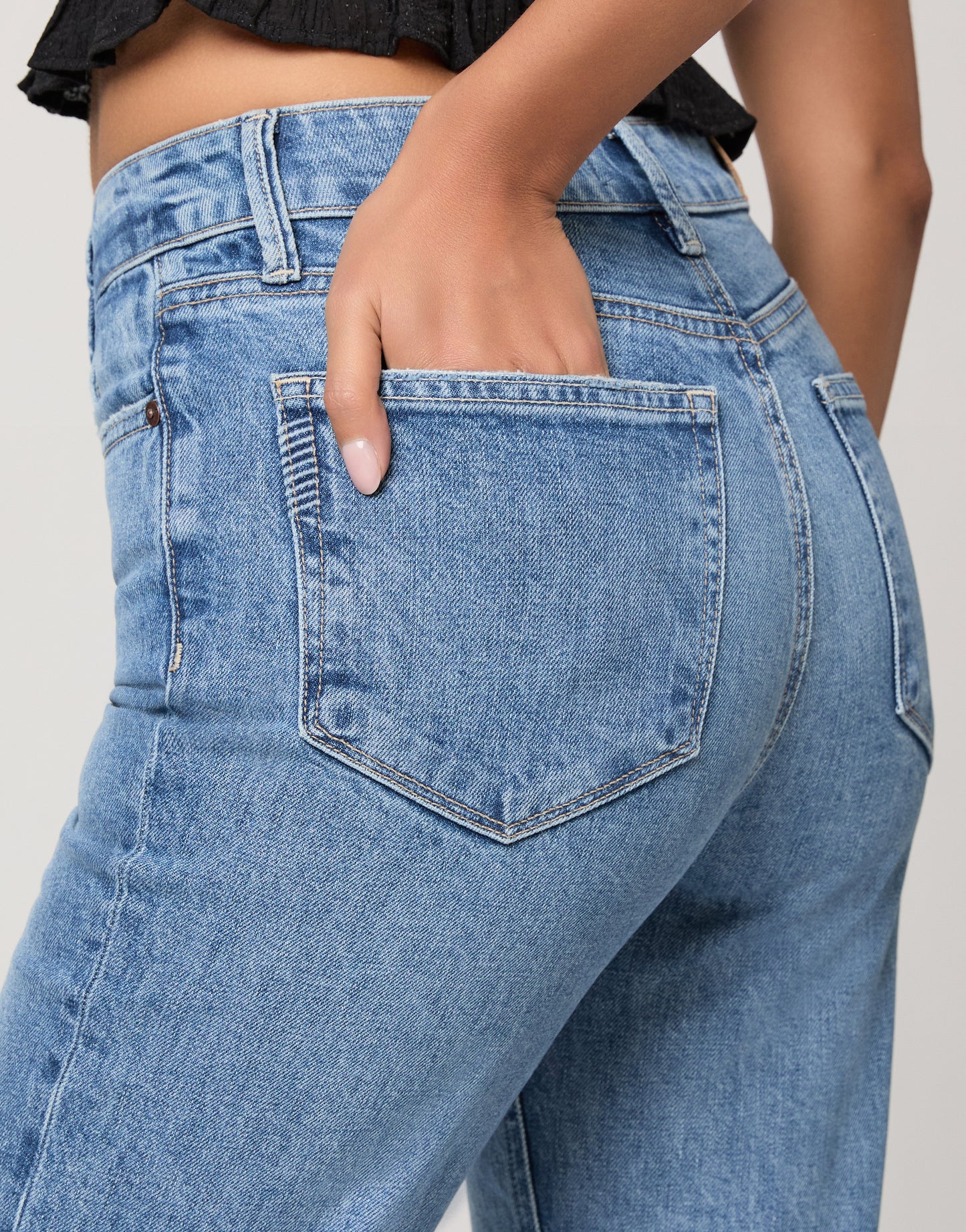 Woman wearing a black top and blue jeans on a white background