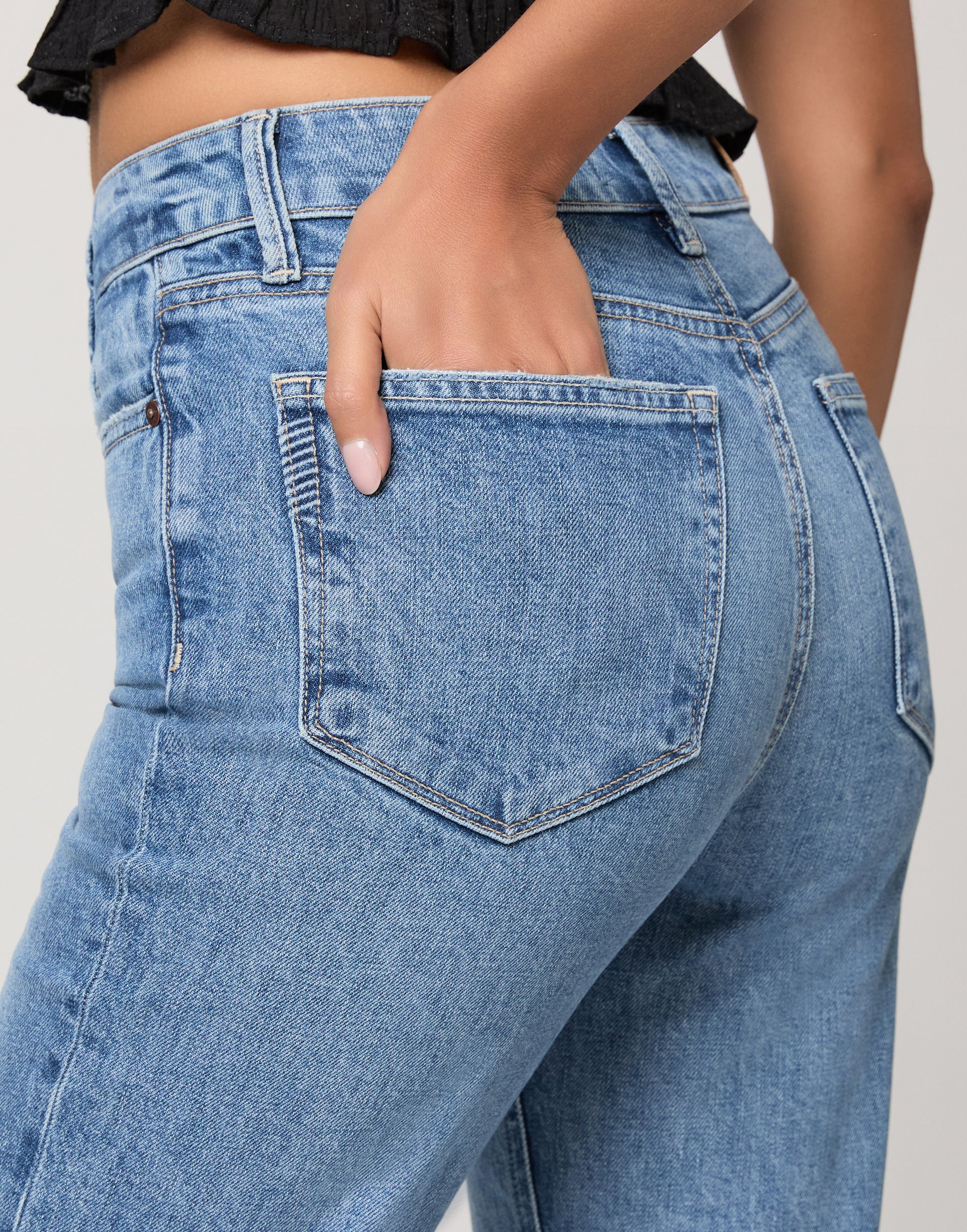 Woman wearing a black top and blue jeans on a white background