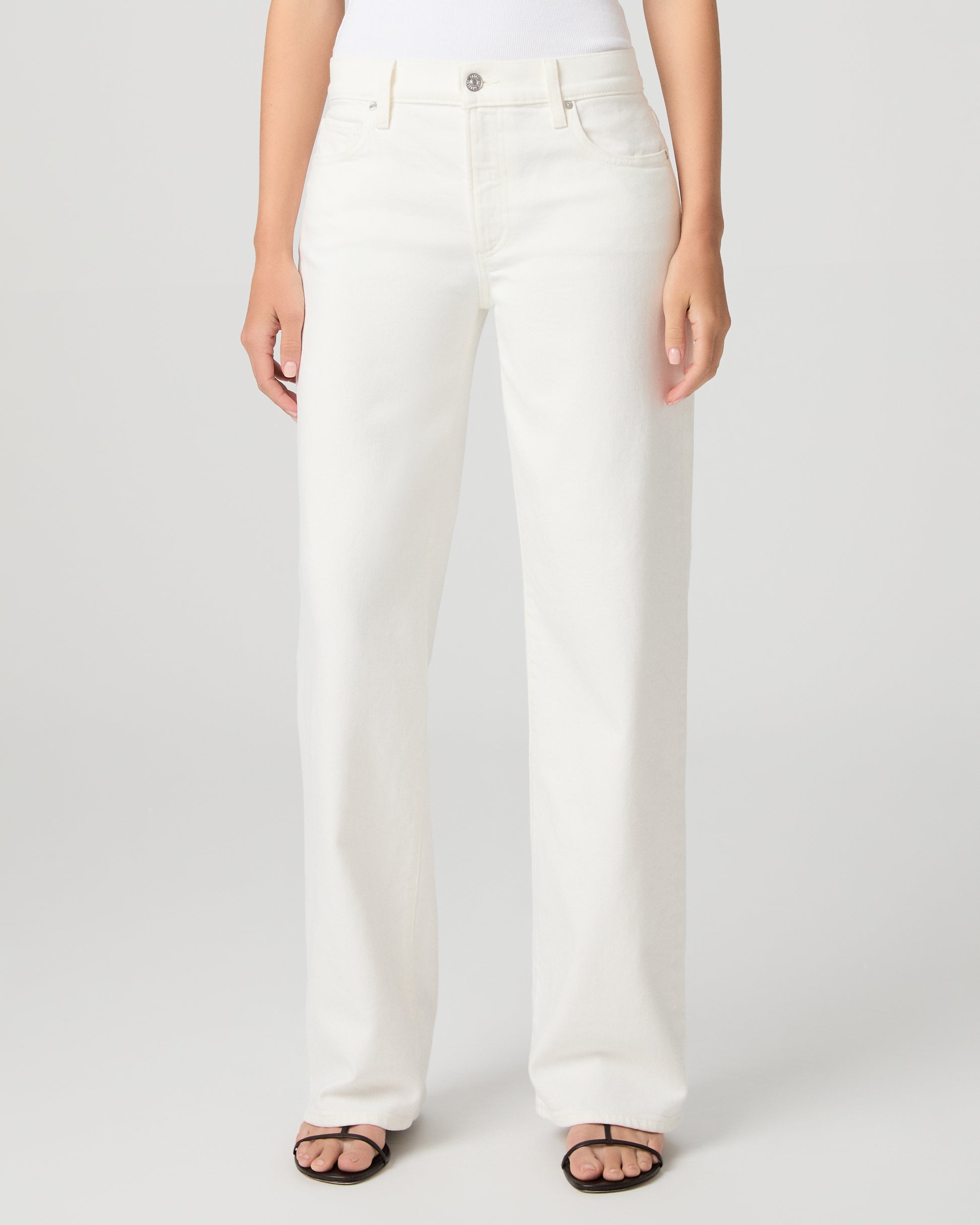 Women wearing a white tank paired with white jeans and a black belt with black sandals 
