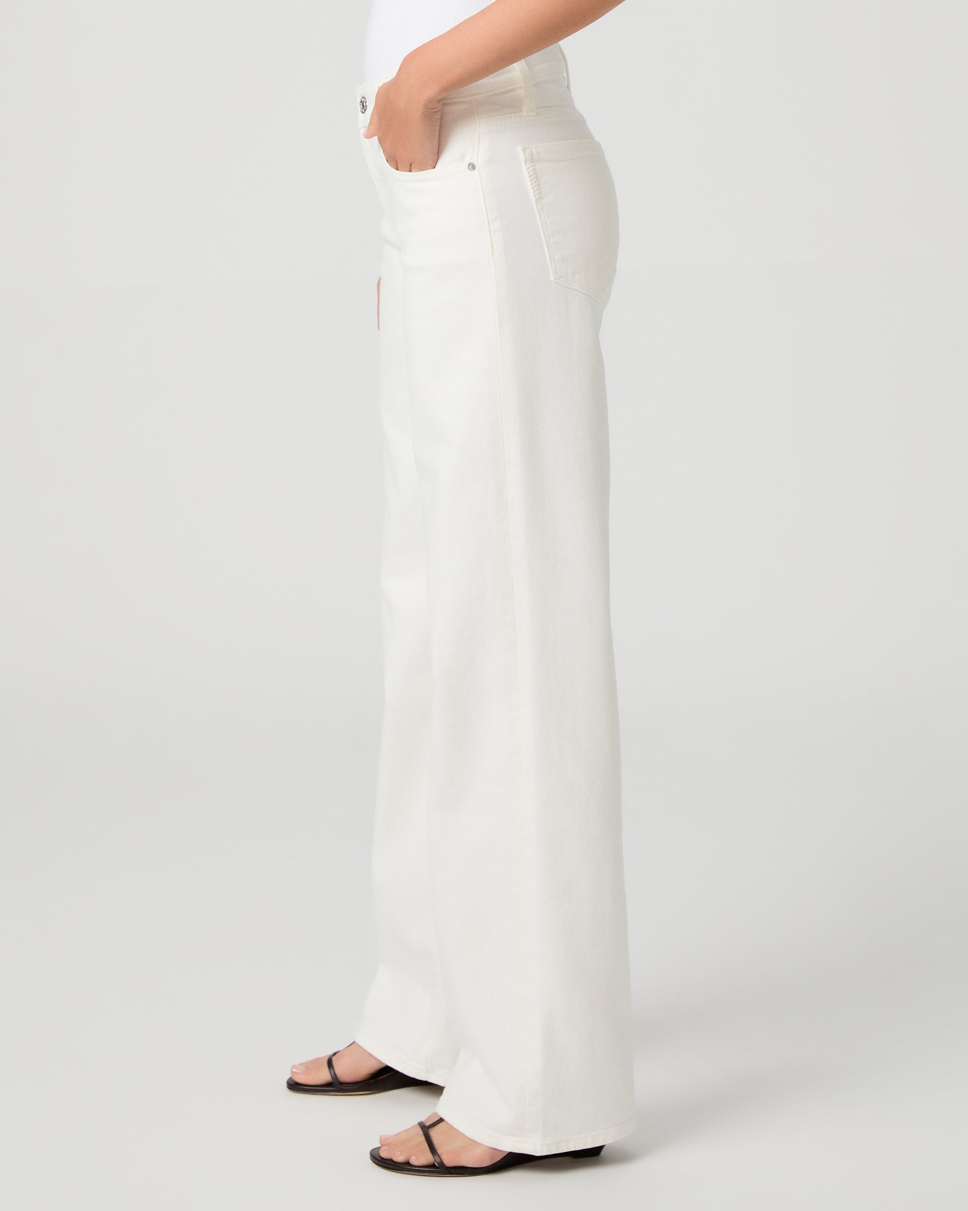 Women wearing a white tank paired with white jeans and a black belt with black sandals 