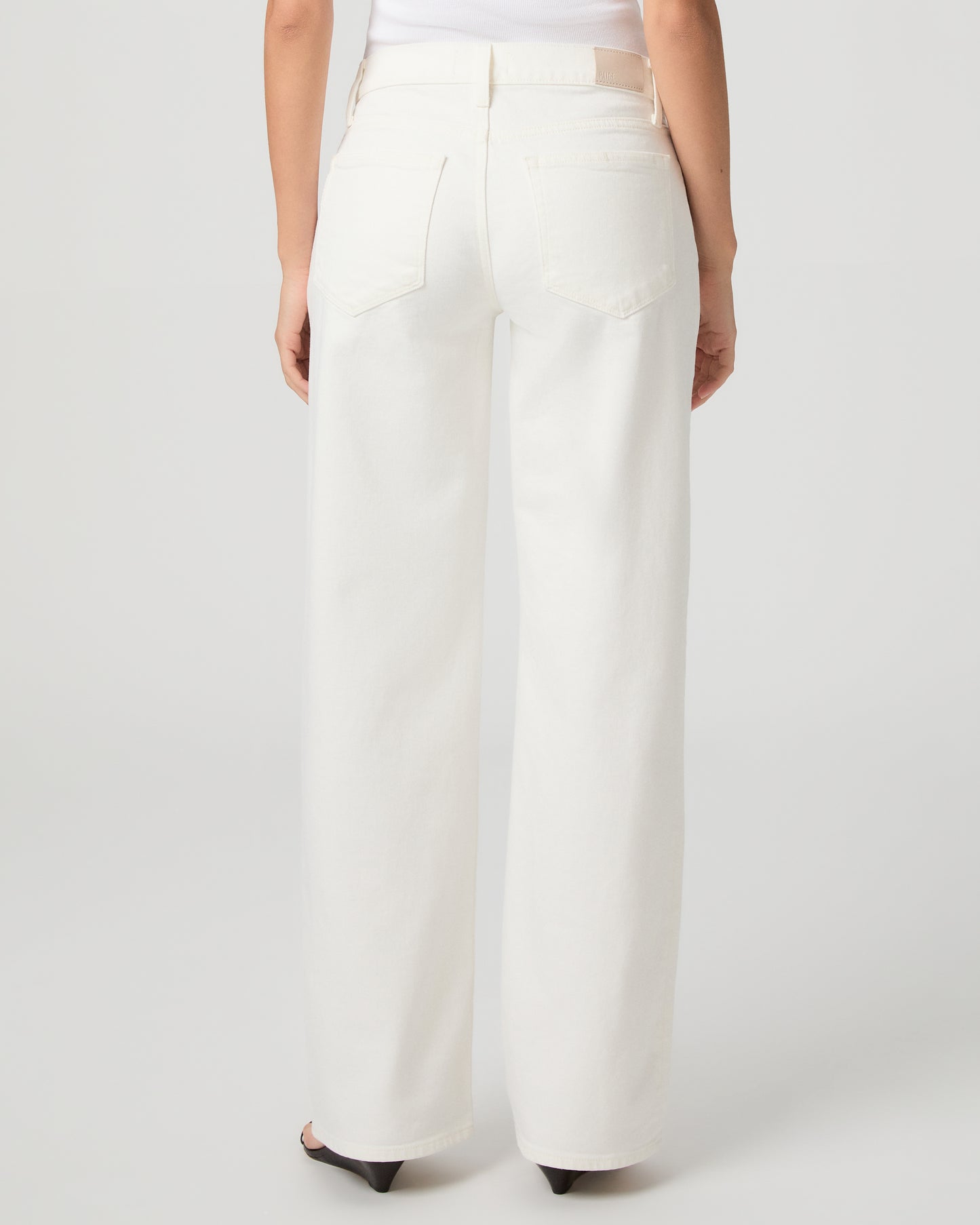Women wearing a white tank paired with white jeans and a black belt with black sandals 
