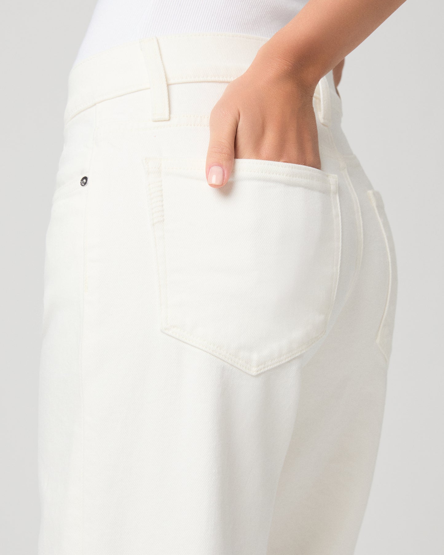 Women wearing a white tank paired with white jeans and a black belt with black sandals 