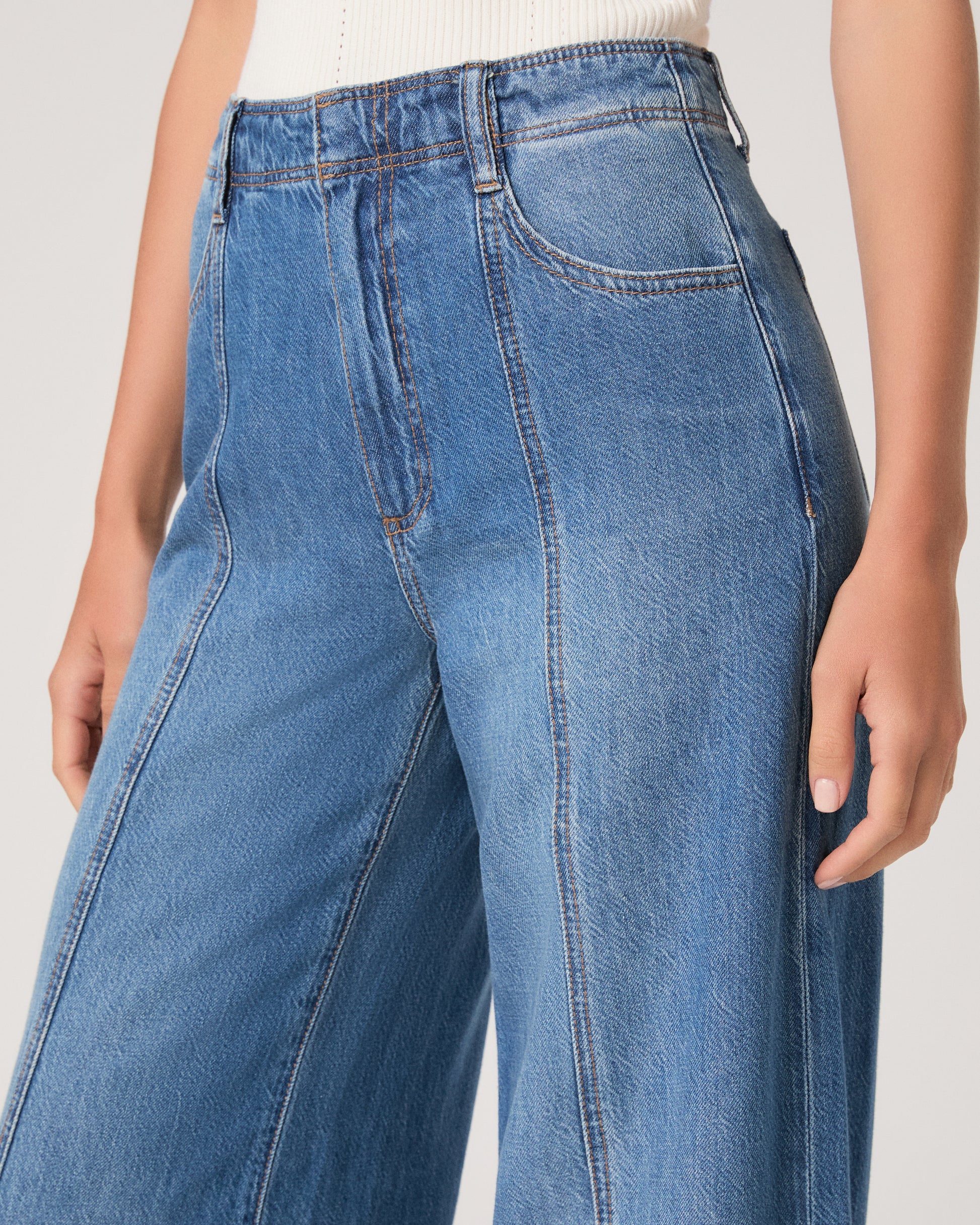 Woman wearing a denim jacket, white top and medium wash denim on a white background