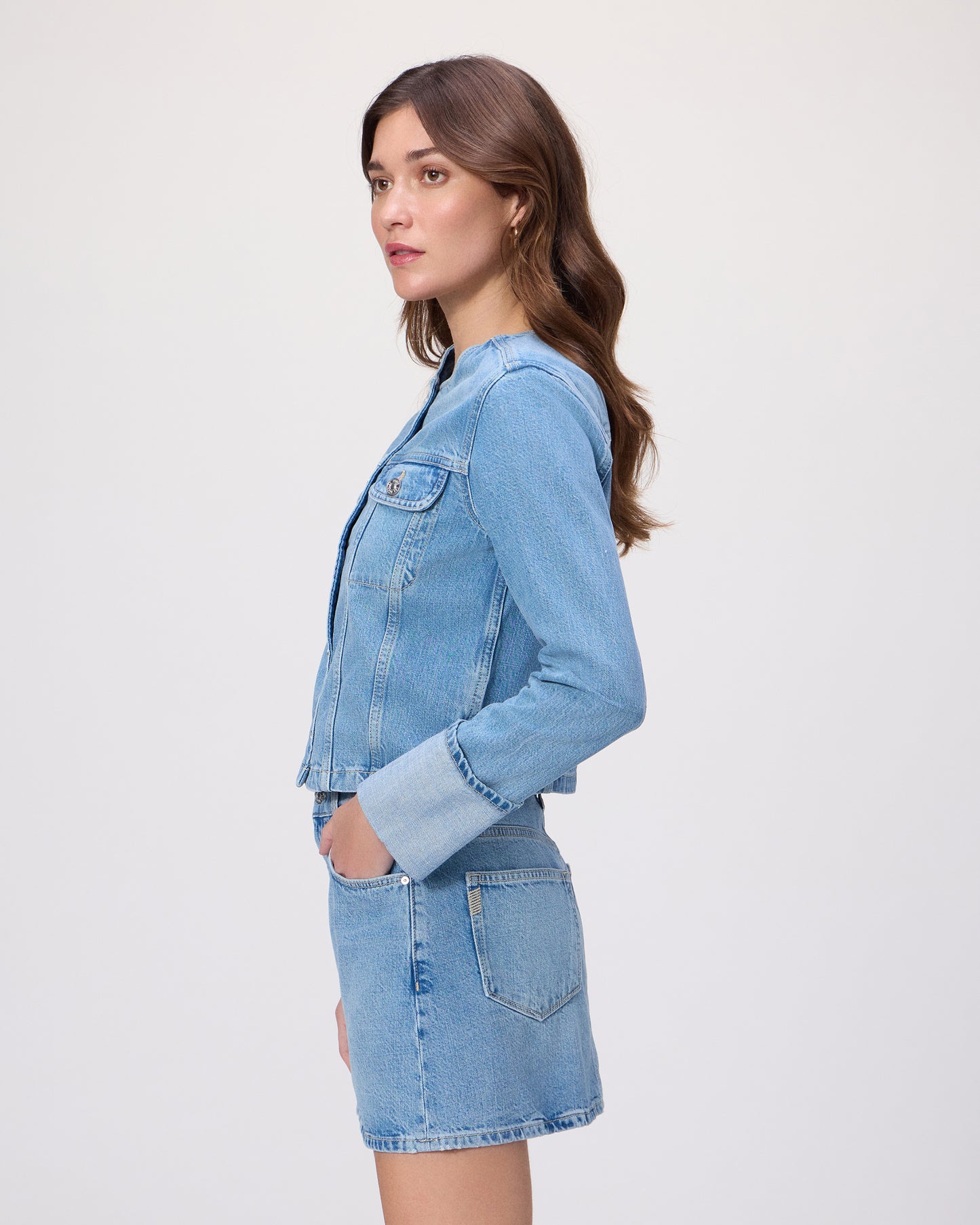 Woman wearing a blue denim jacket and skirt on a white background