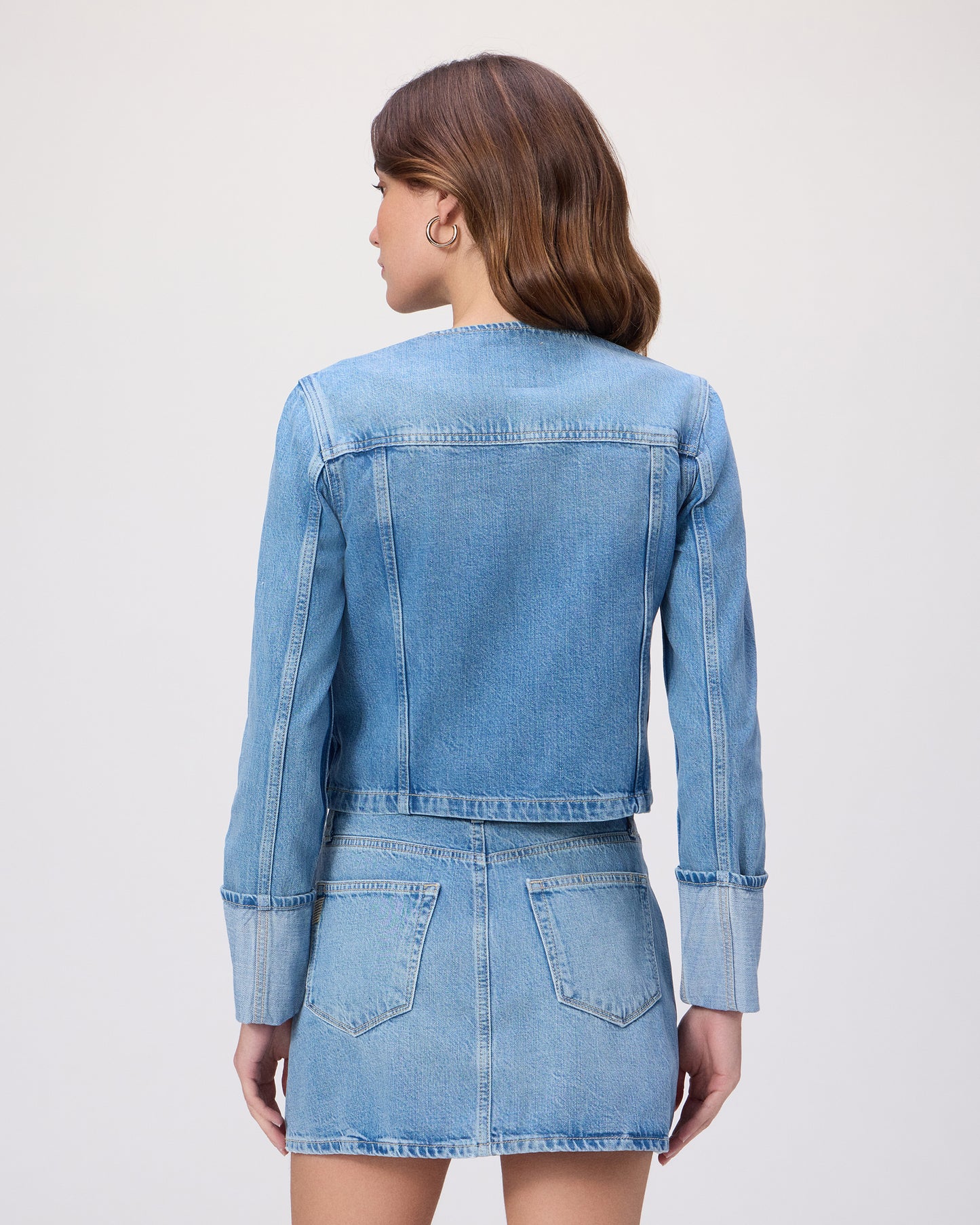 Woman wearing a blue denim jacket and skirt on a white background