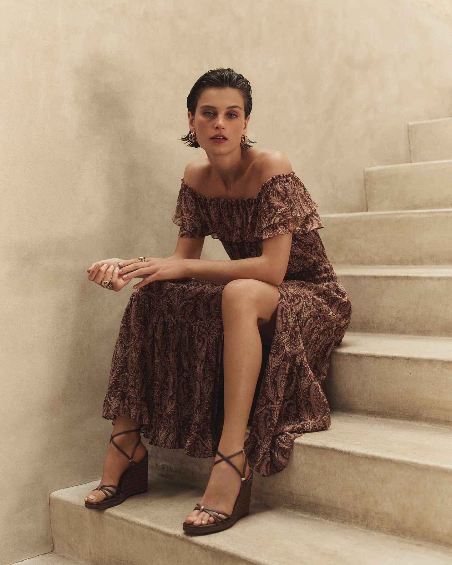 Woman in a patterned brown dress sitting on a staircase