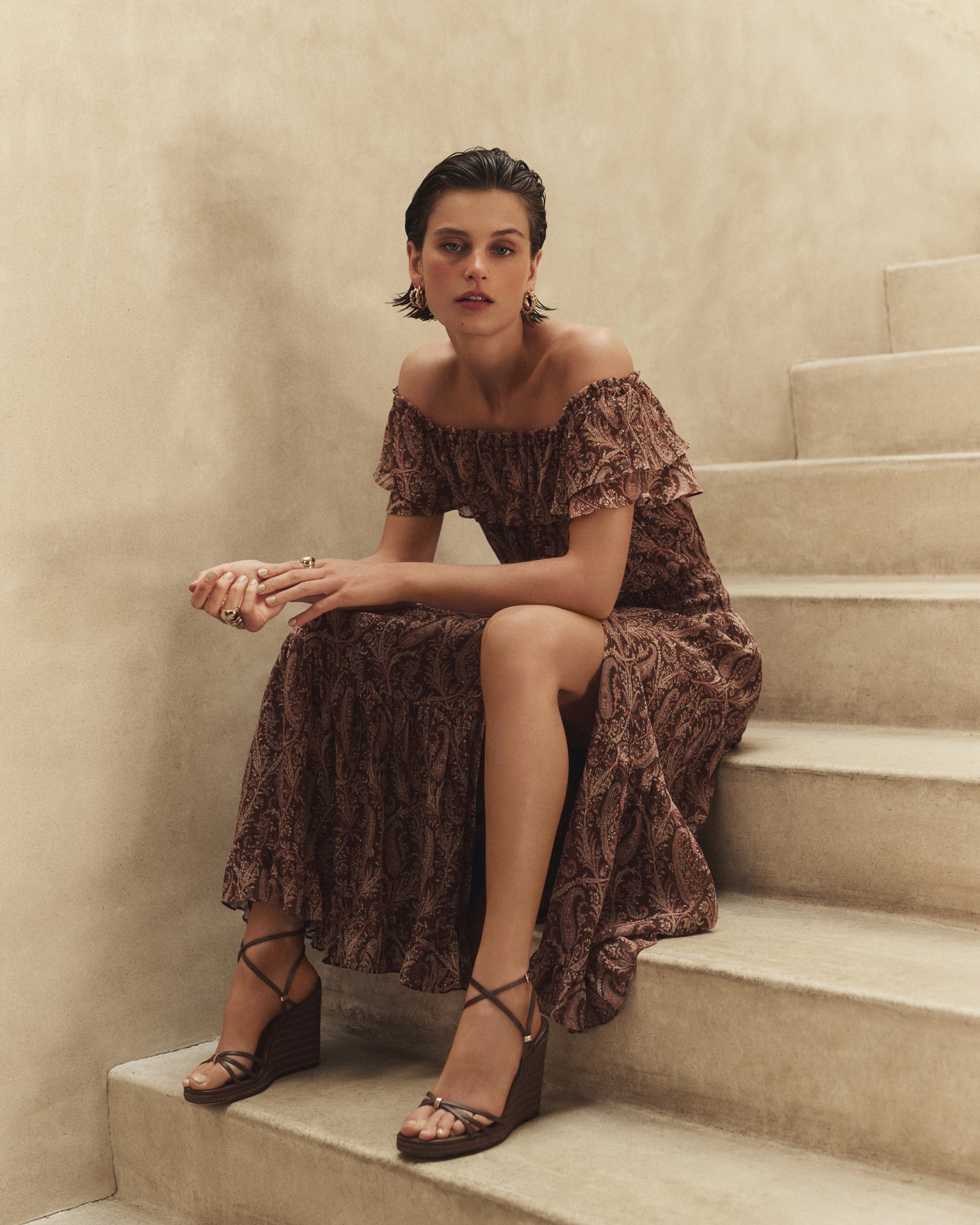 Woman in a patterned brown dress sitting on a staircase