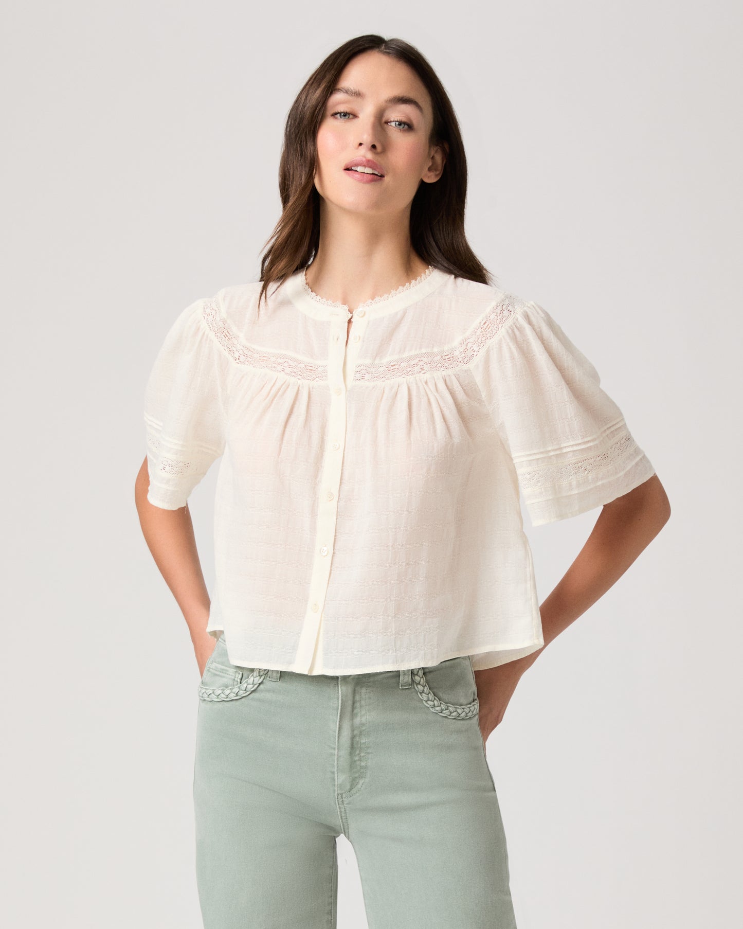 Model wearing a white top paired with light green pants 