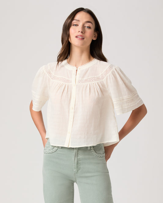 Model wearing a white top paired with light green pants 