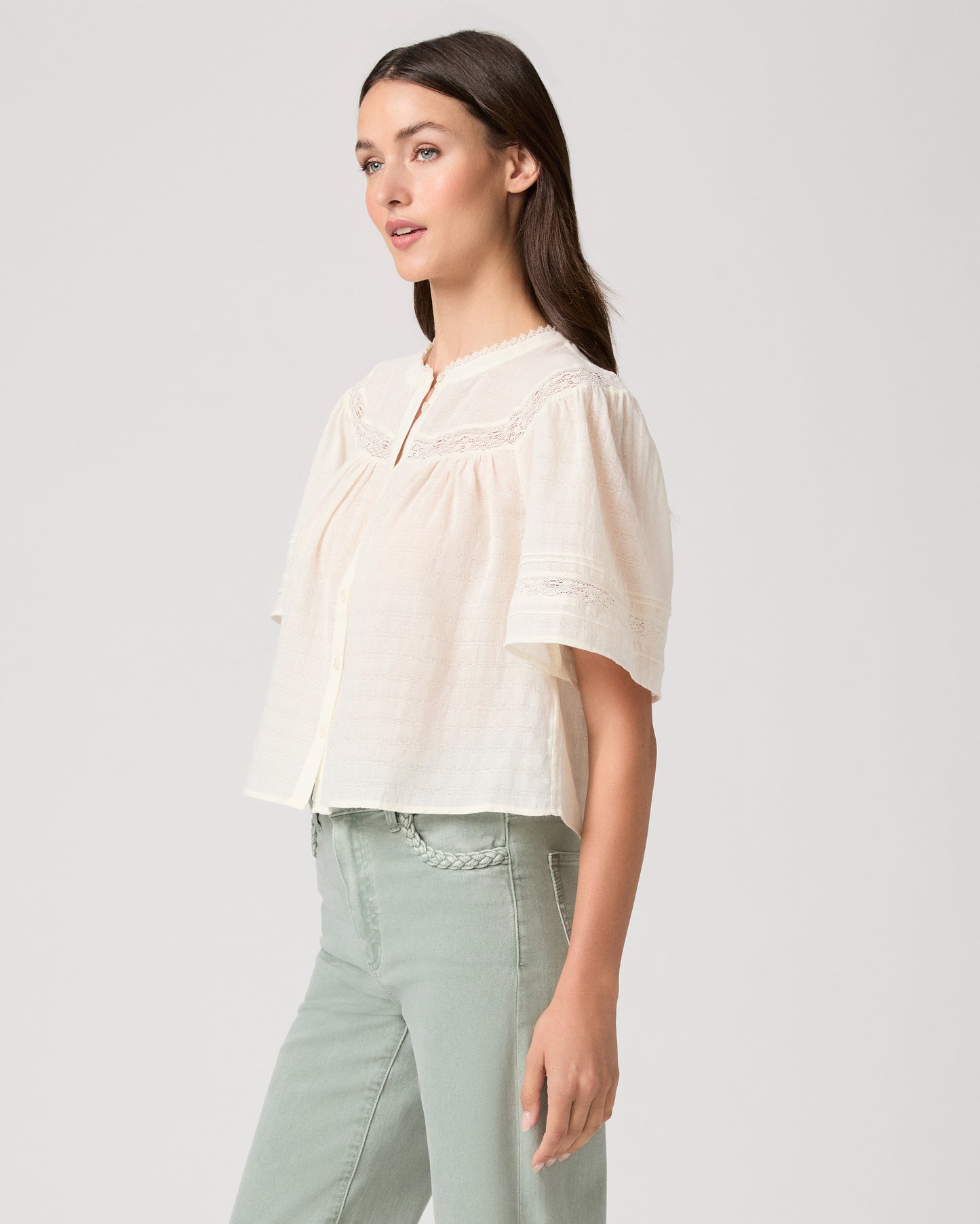 Pasadena Blouse - Ivory Model wearing a white top paired with light green pants with brown sandals