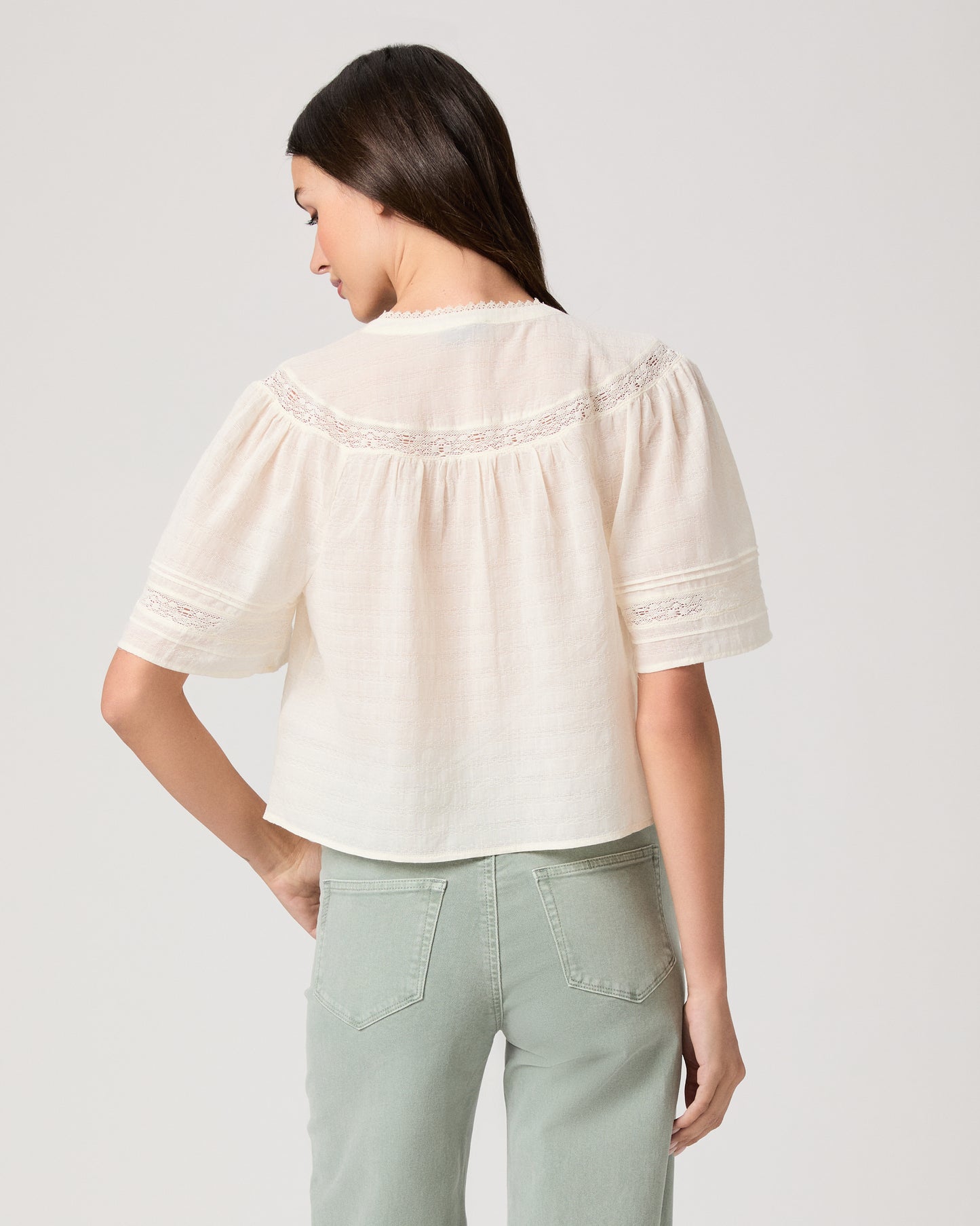Pasadena Blouse - Ivory Model wearing a white top paired with light green pants with brown sandals